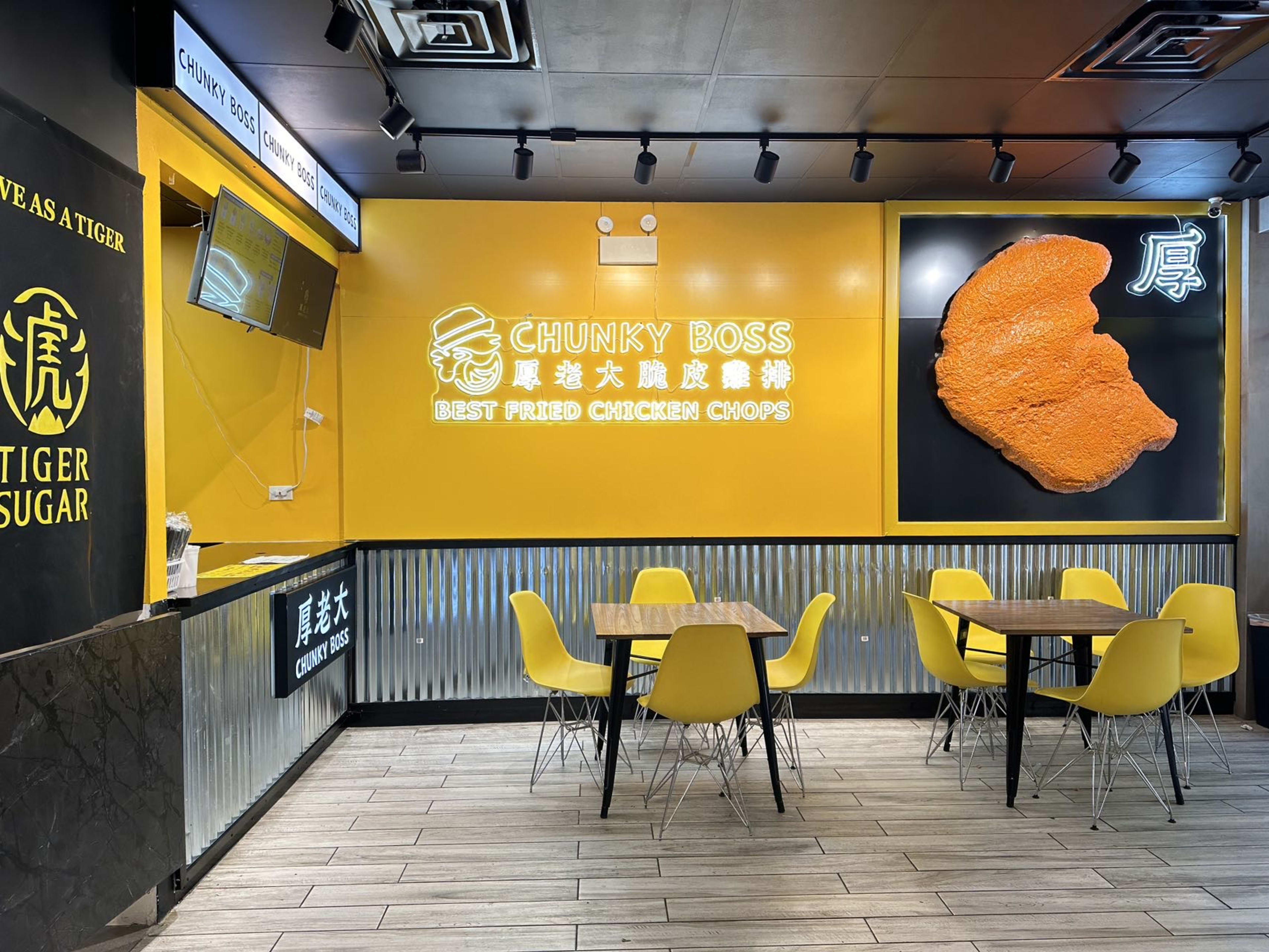 Bright yellow interior of Chunky Boss, with two wooden tables and yellow chairs