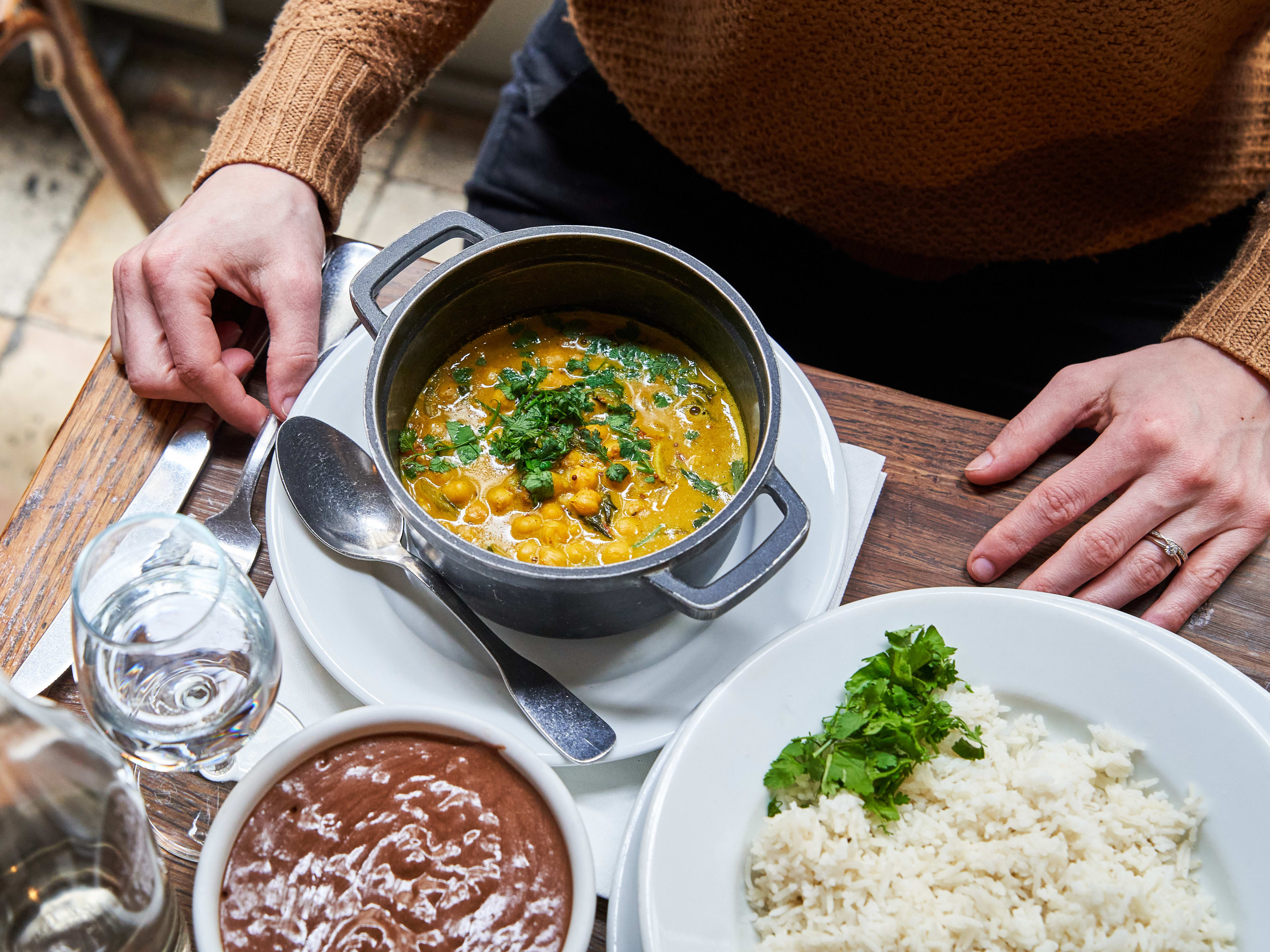 Stew dish served in cast iron pot with side of rice at Cinq-Mars