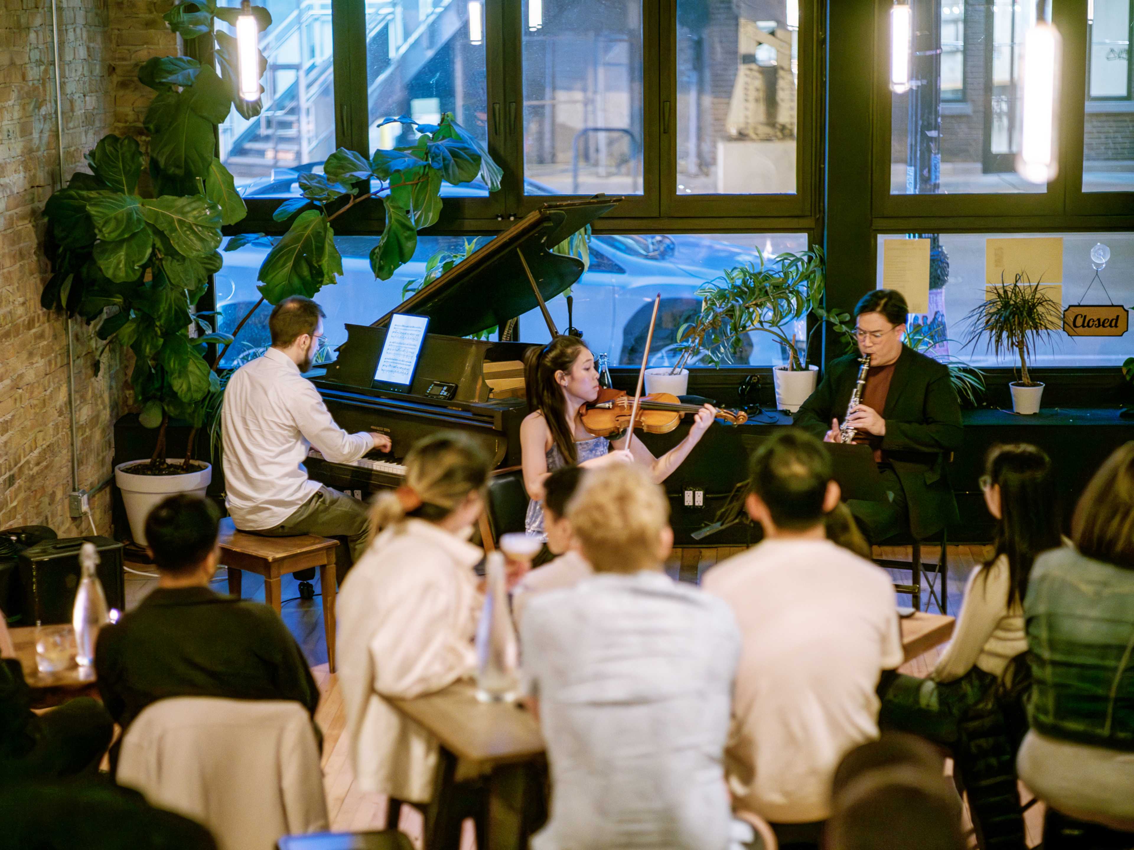 A music trio playing to an audience sitting at tables.