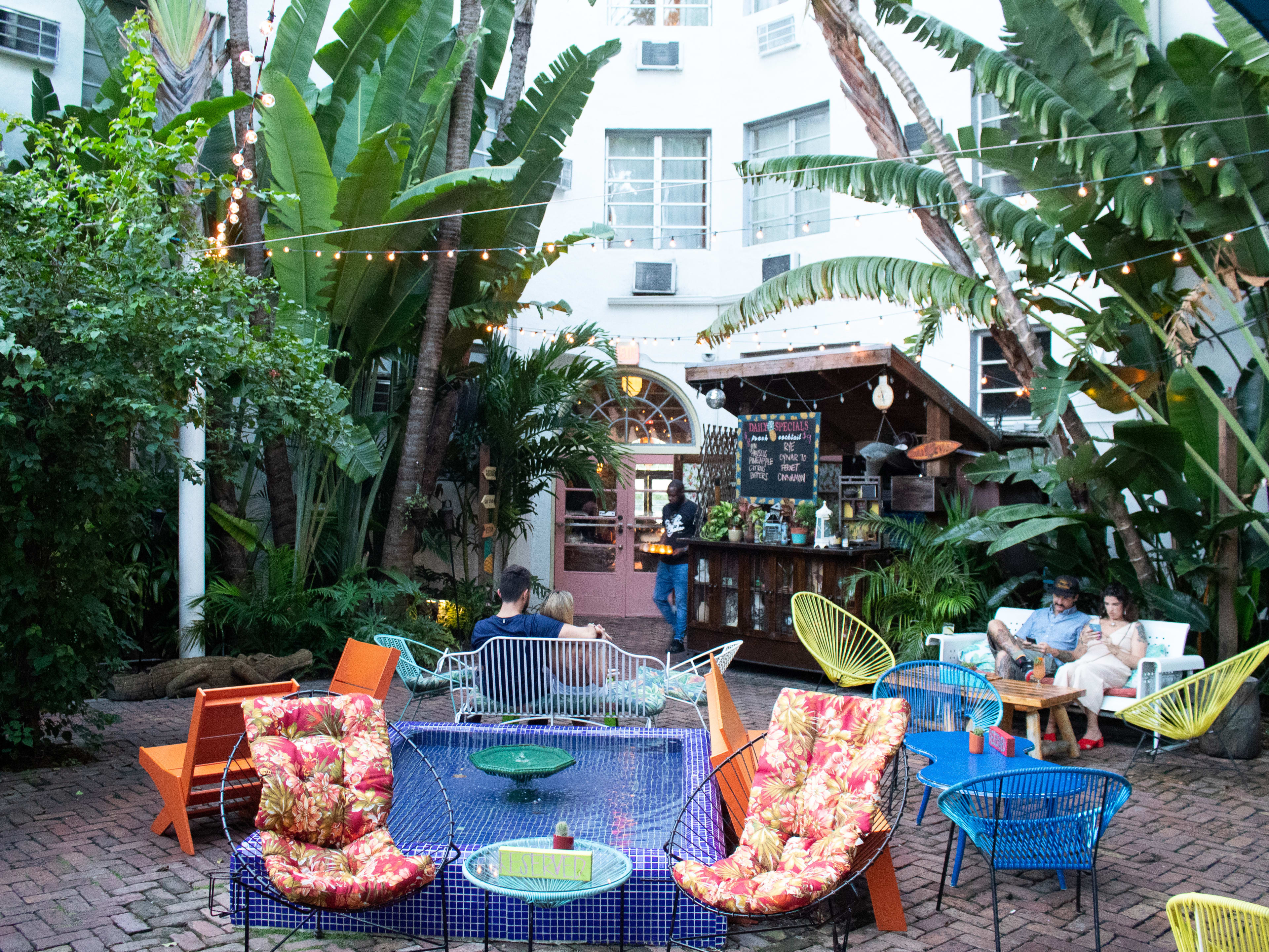 outdoor patio with tropical trees and plants and colorful furniture