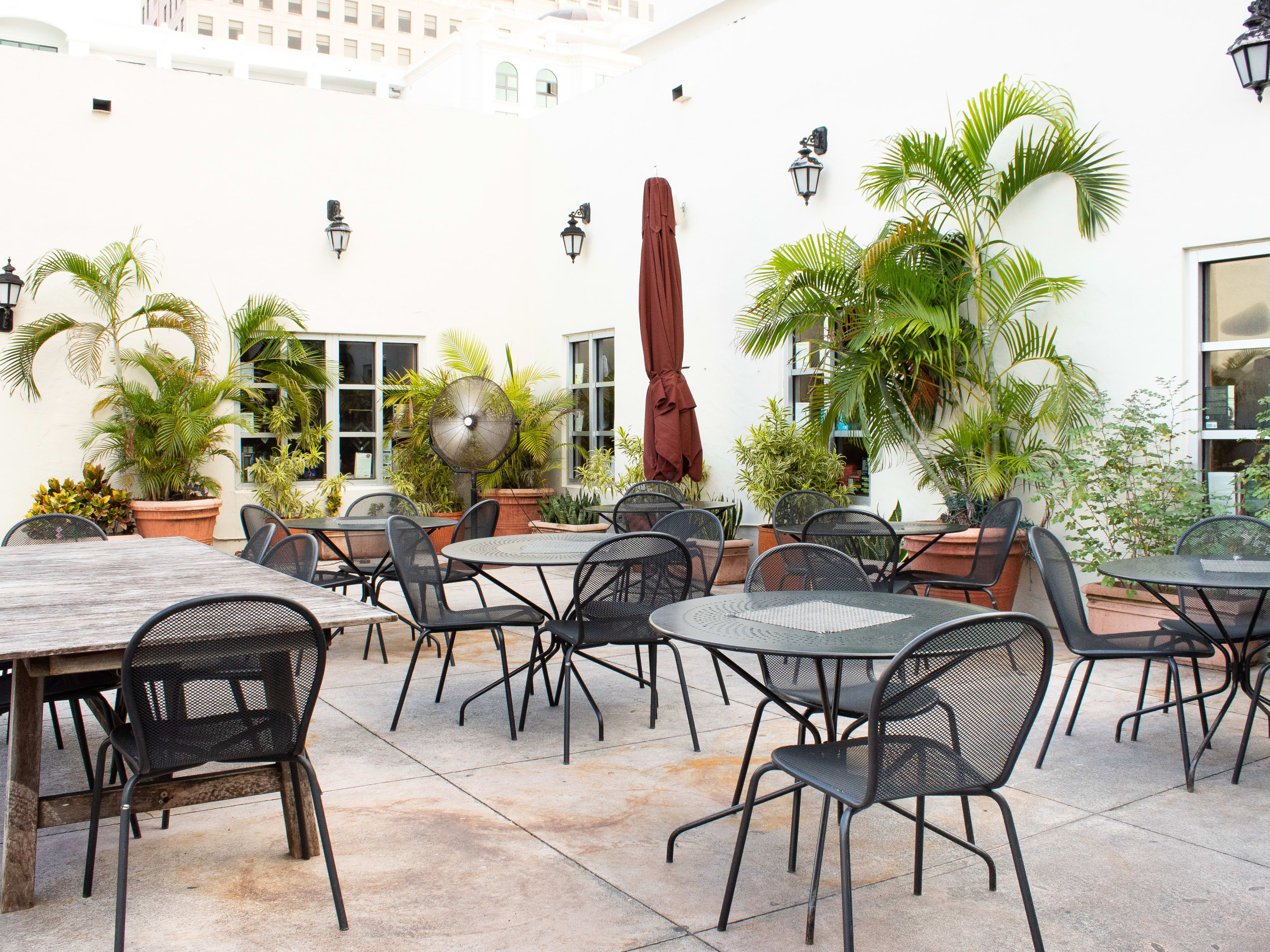 outdoor patios with closed umbrellas, tables and chairs.