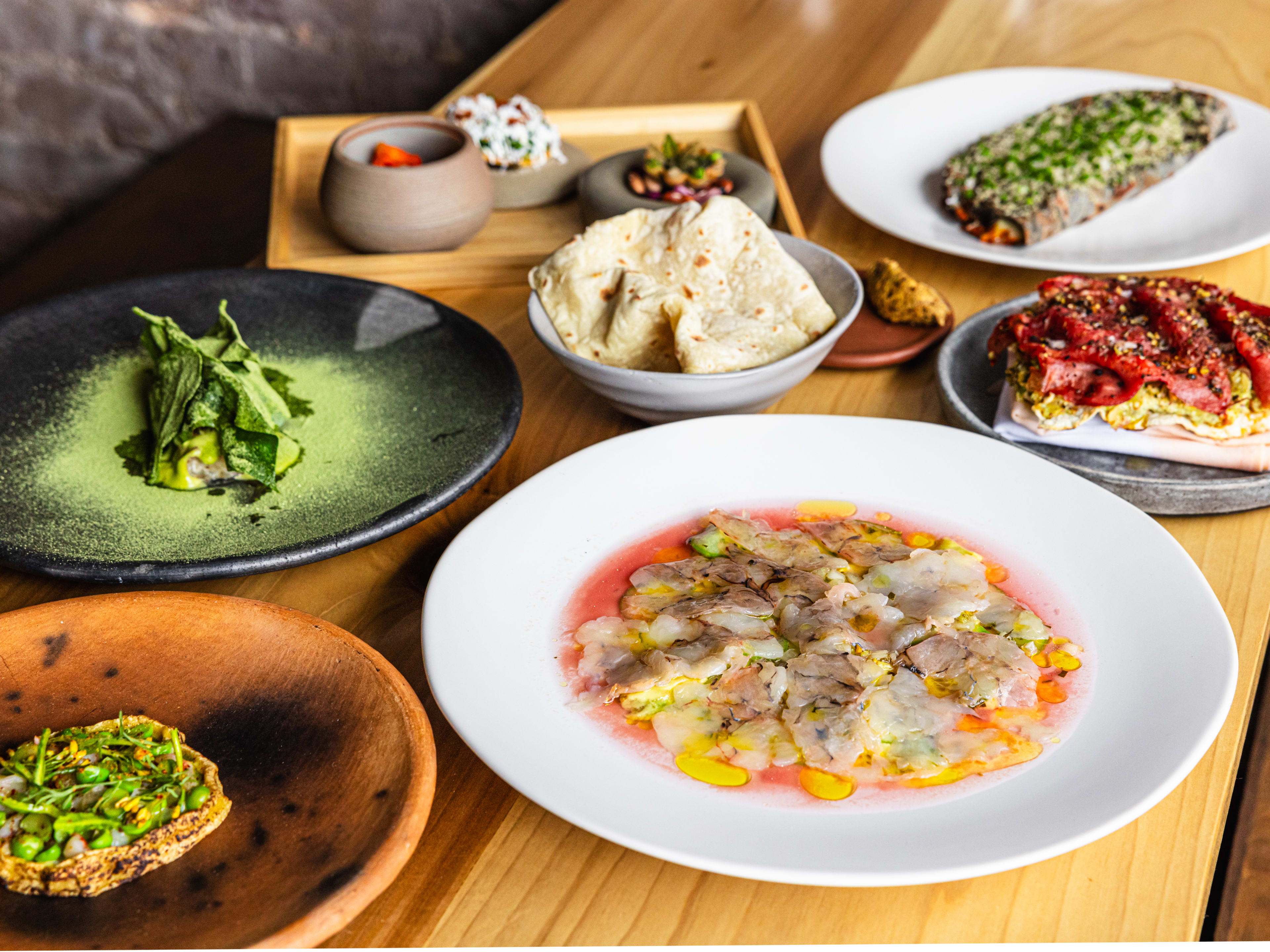 A spread of Mexican-inspired small plates on a wooden table.