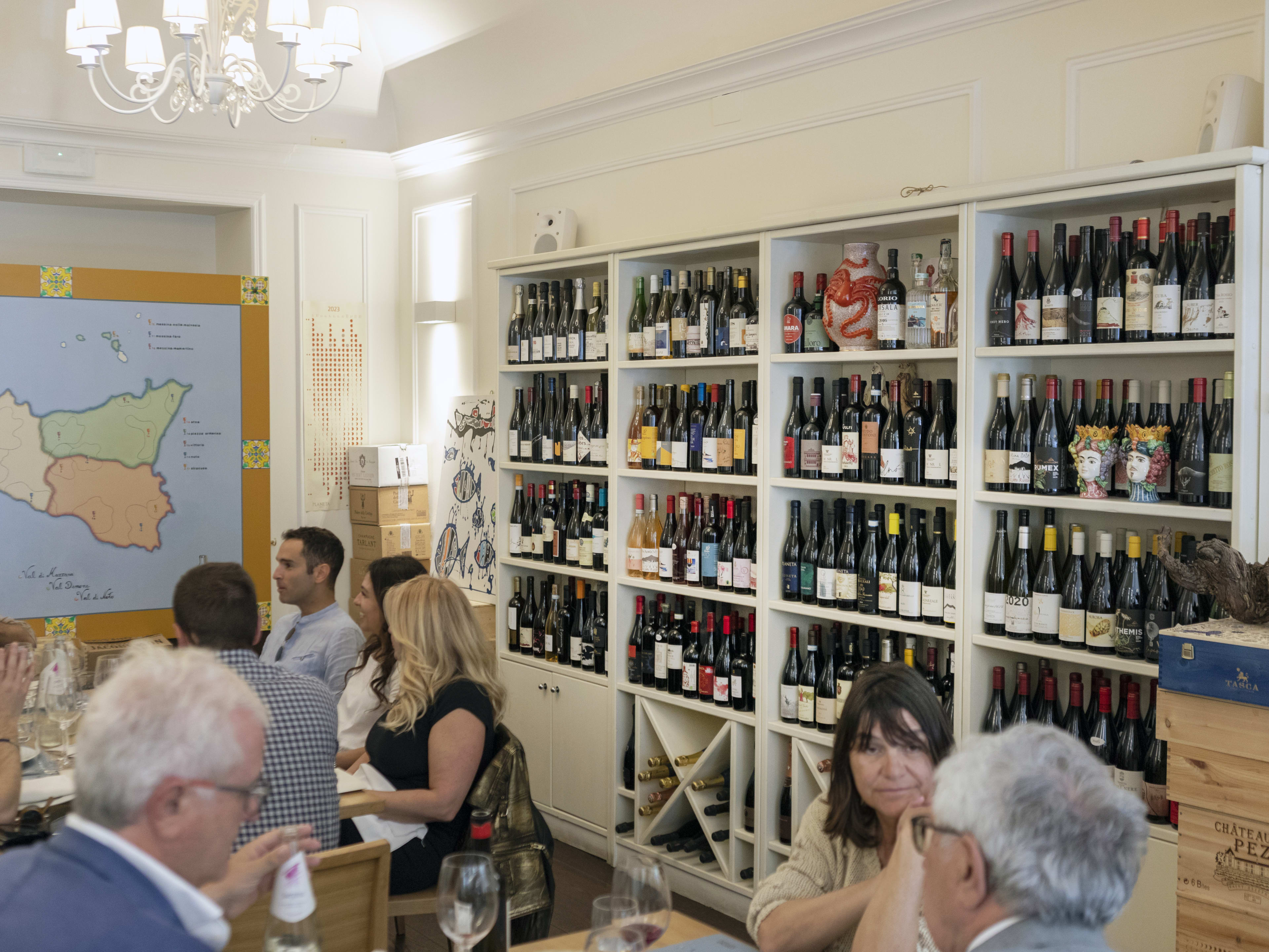 Interior dining room during busy dinner service with shelves of wine bottles at Corona Trattoria