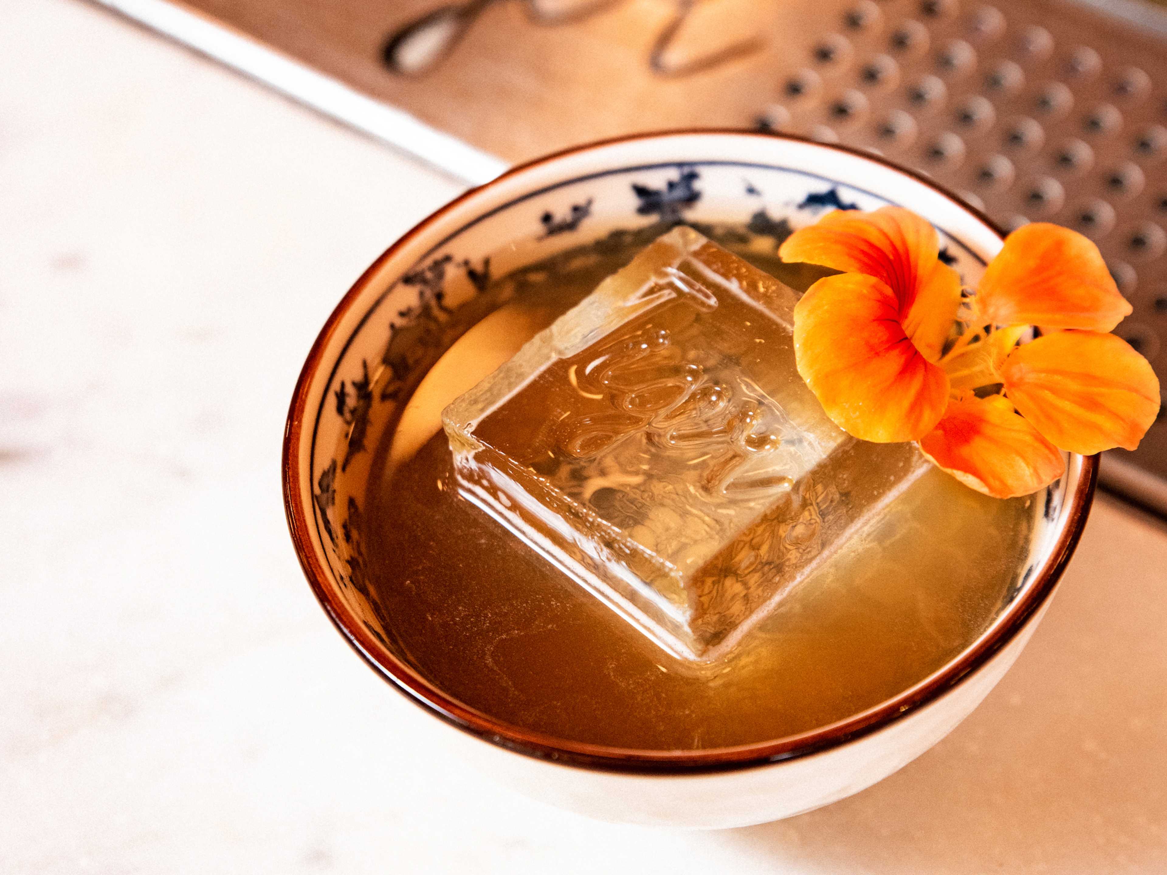 Cocktail served in large teacup and topped with edible flower at Tiger