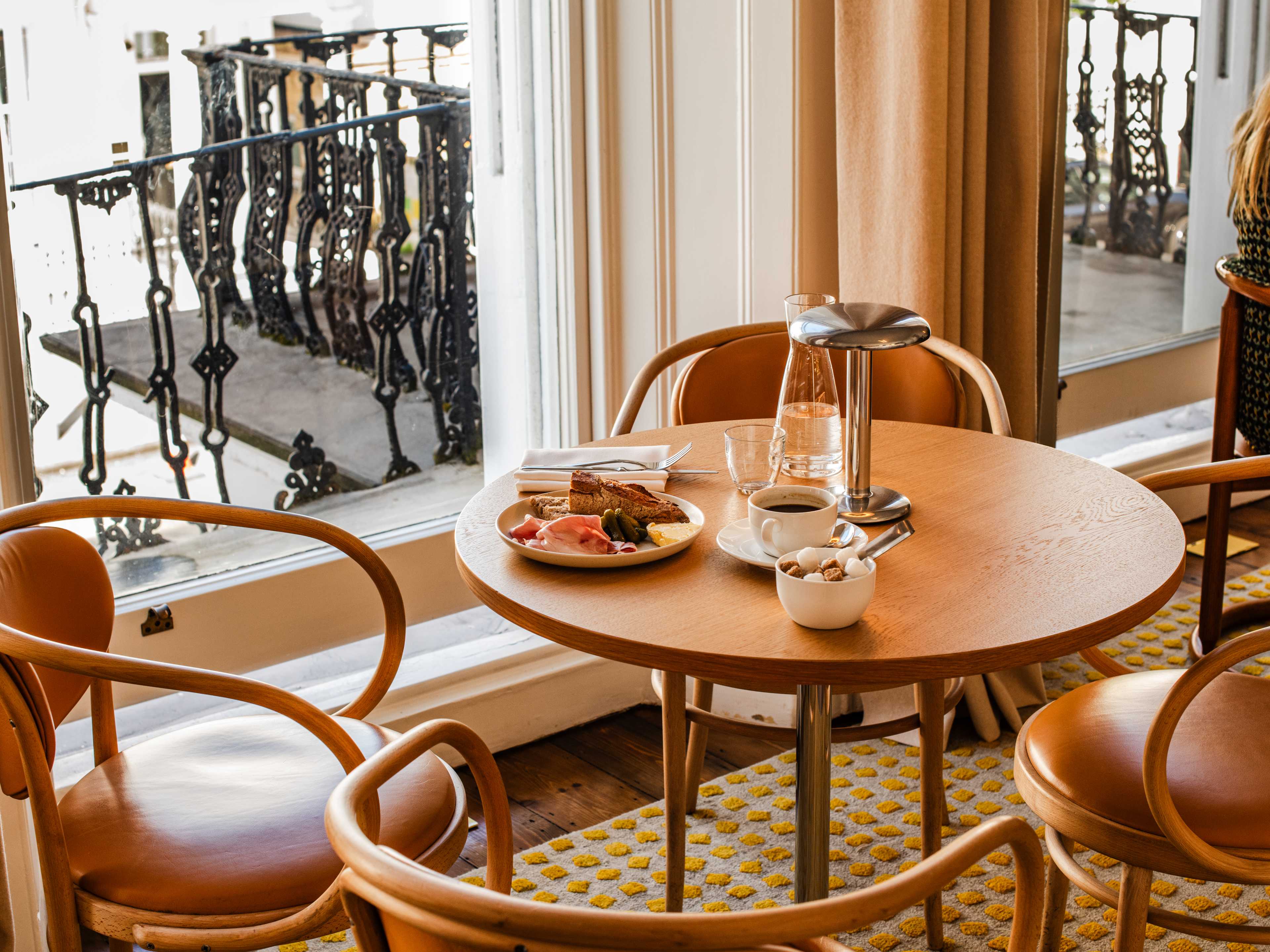 Brown chairs and table with a plate of food and a coffee on it.