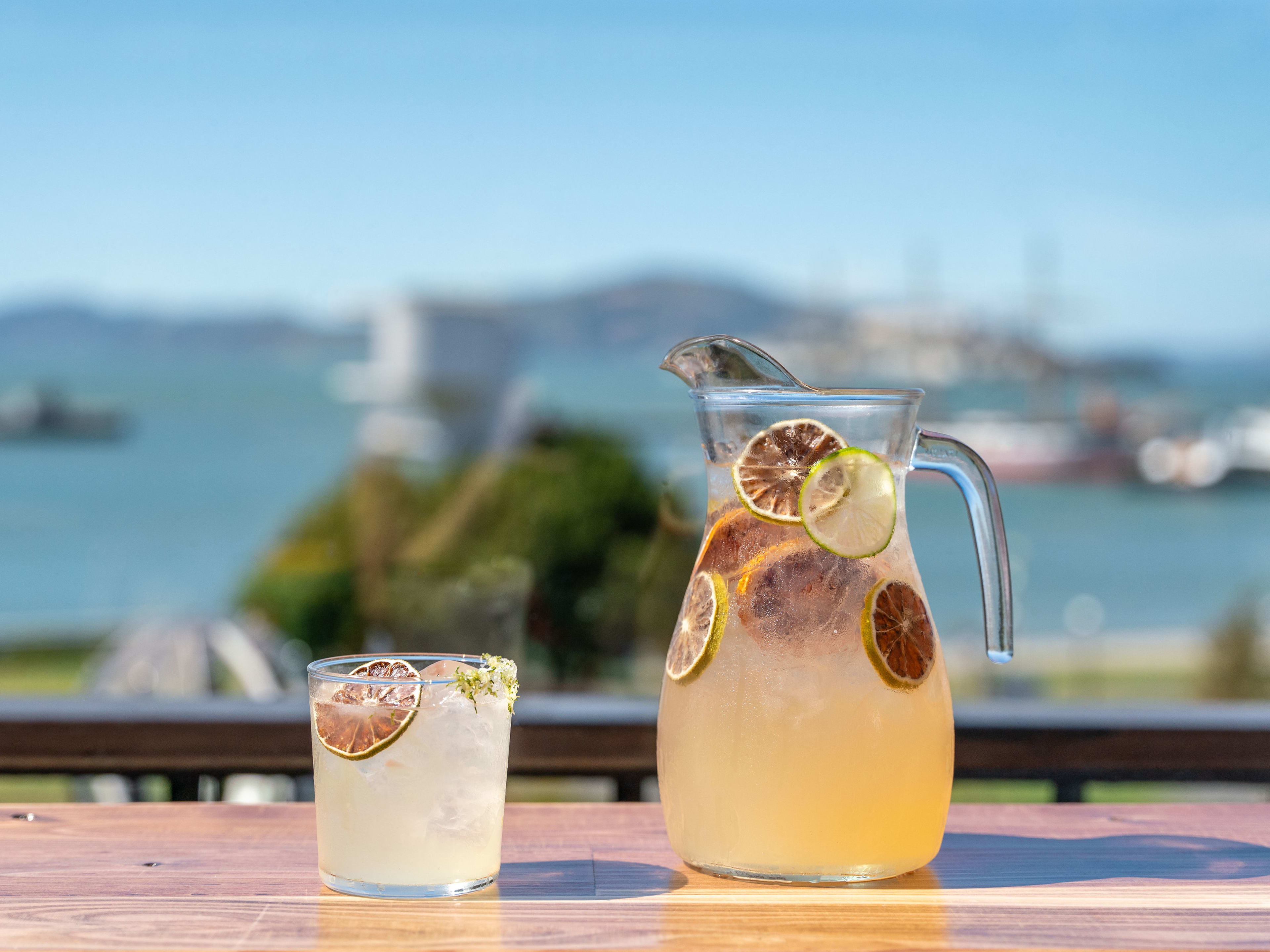 pitcher and glass of cocktail on table overlooking bay