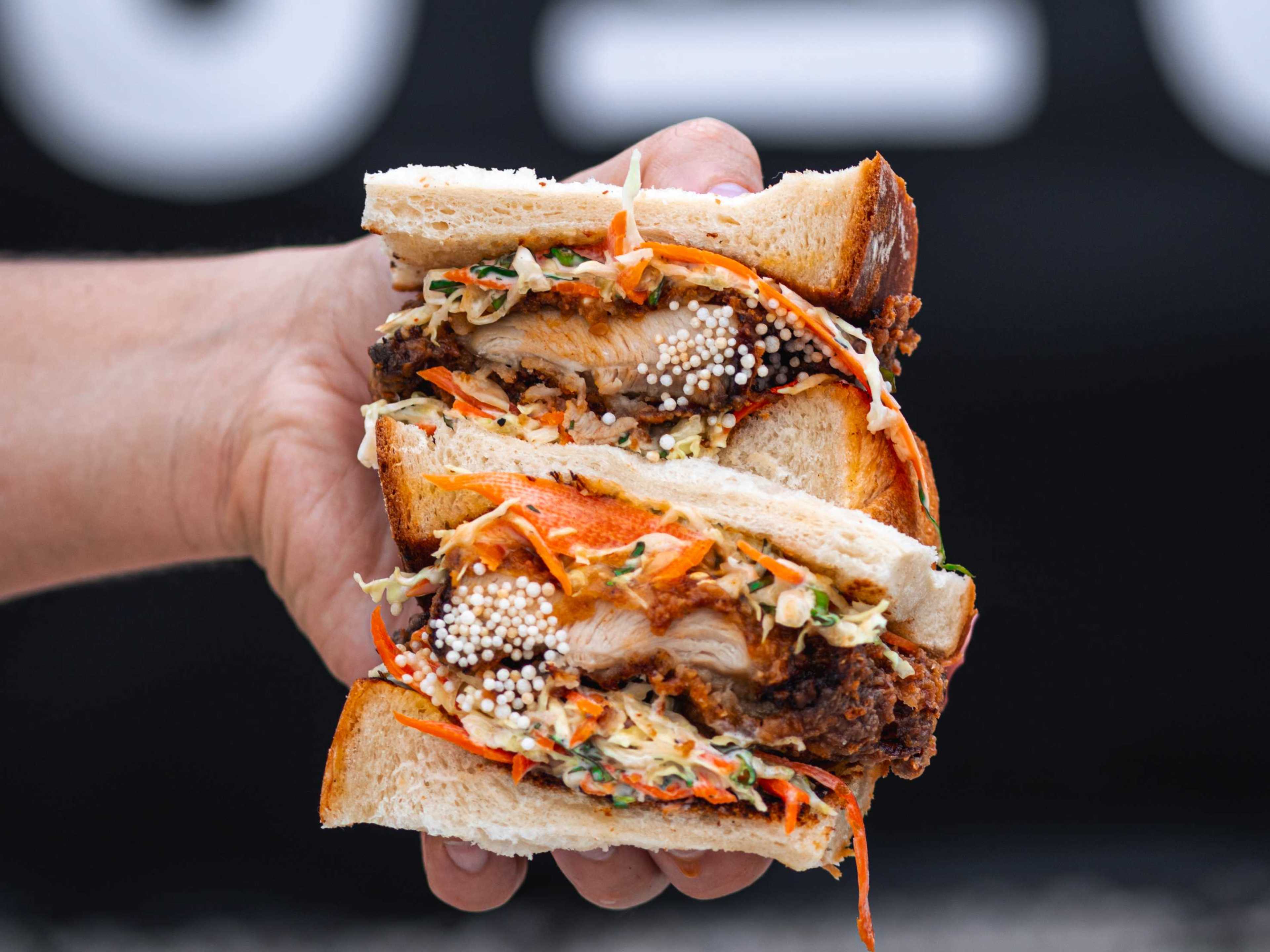 hand holding katsu sandwich cut in half to show filling