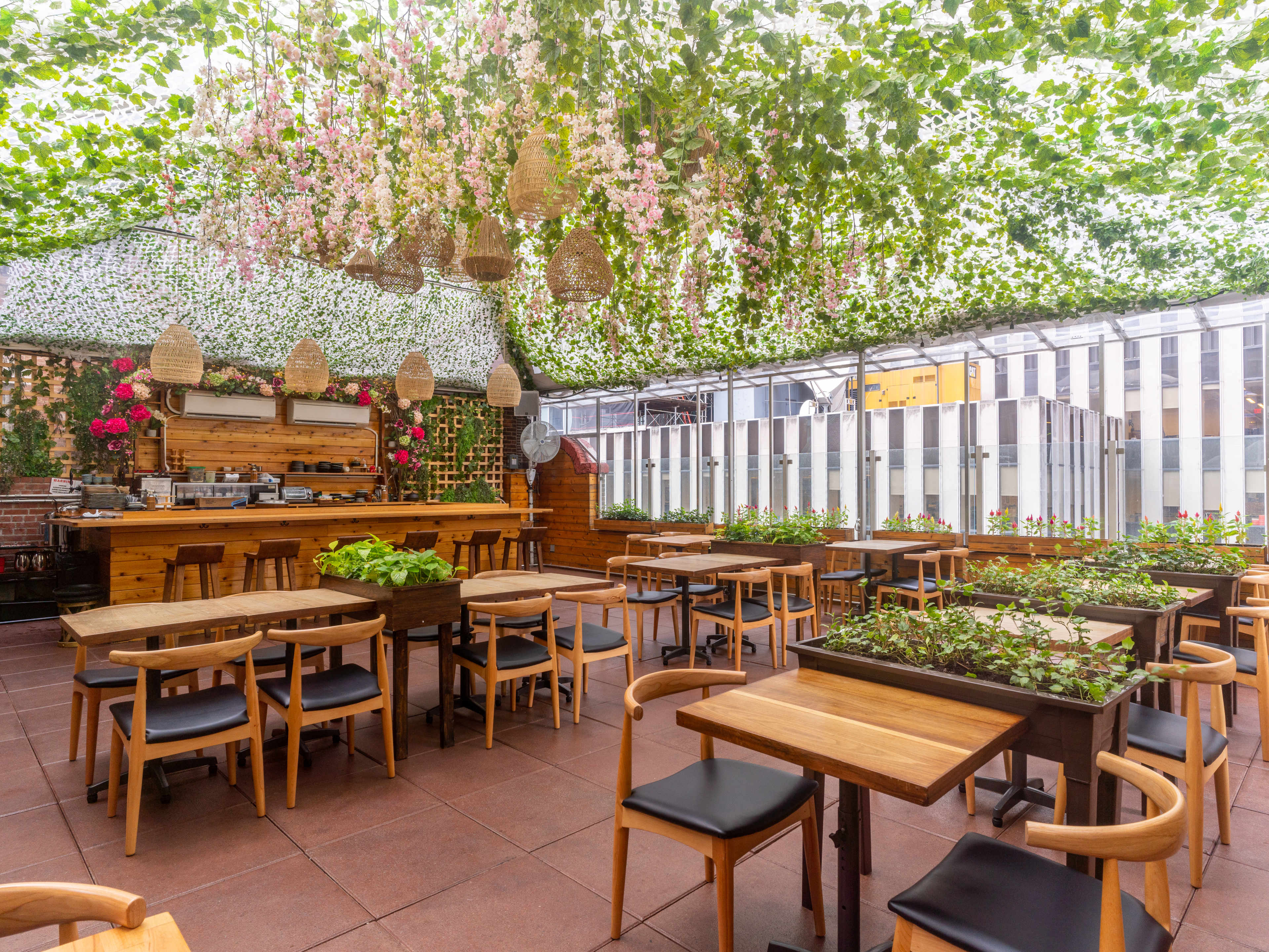 The rooftop of Sushi Lab. The ceiling is covered in foliage drapery with pink flowers and hanging basket lamps.