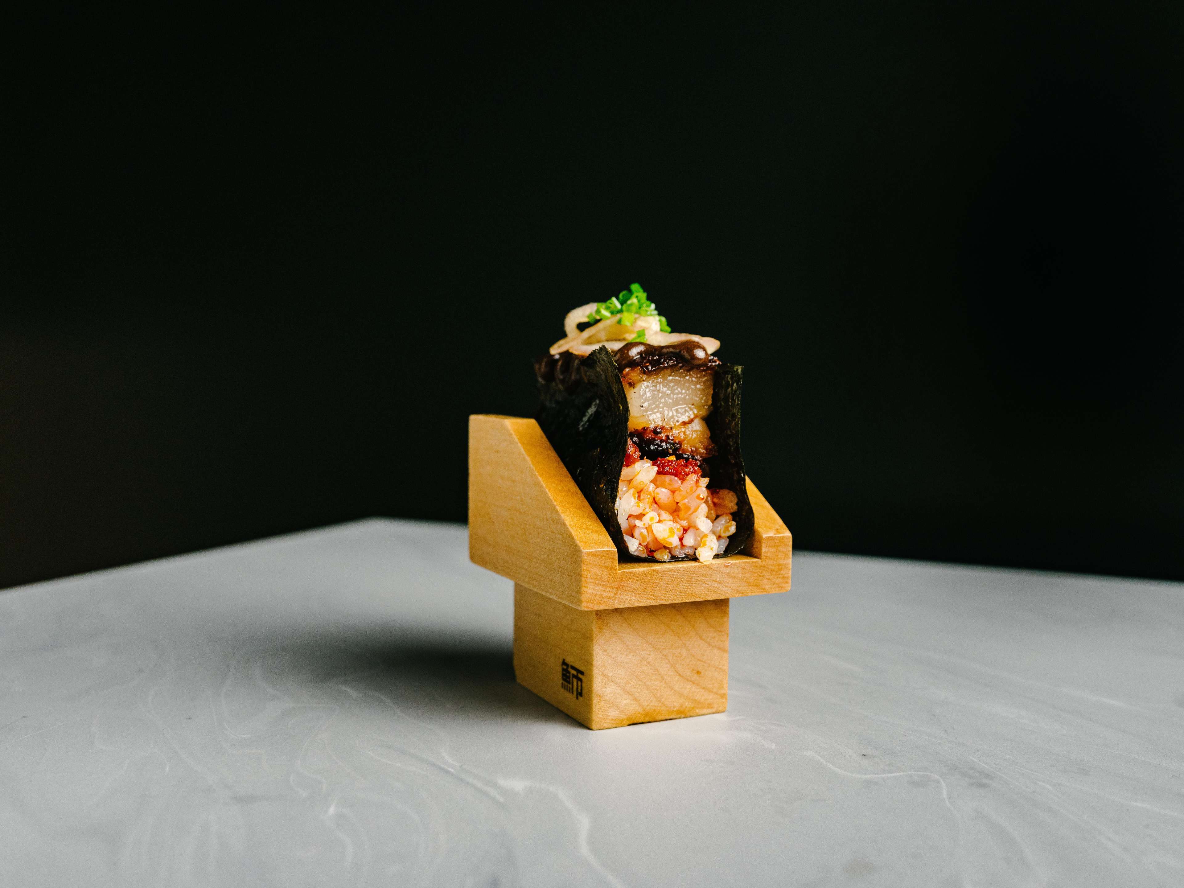 A temaki roll served in a wooden stand from Kamasu.