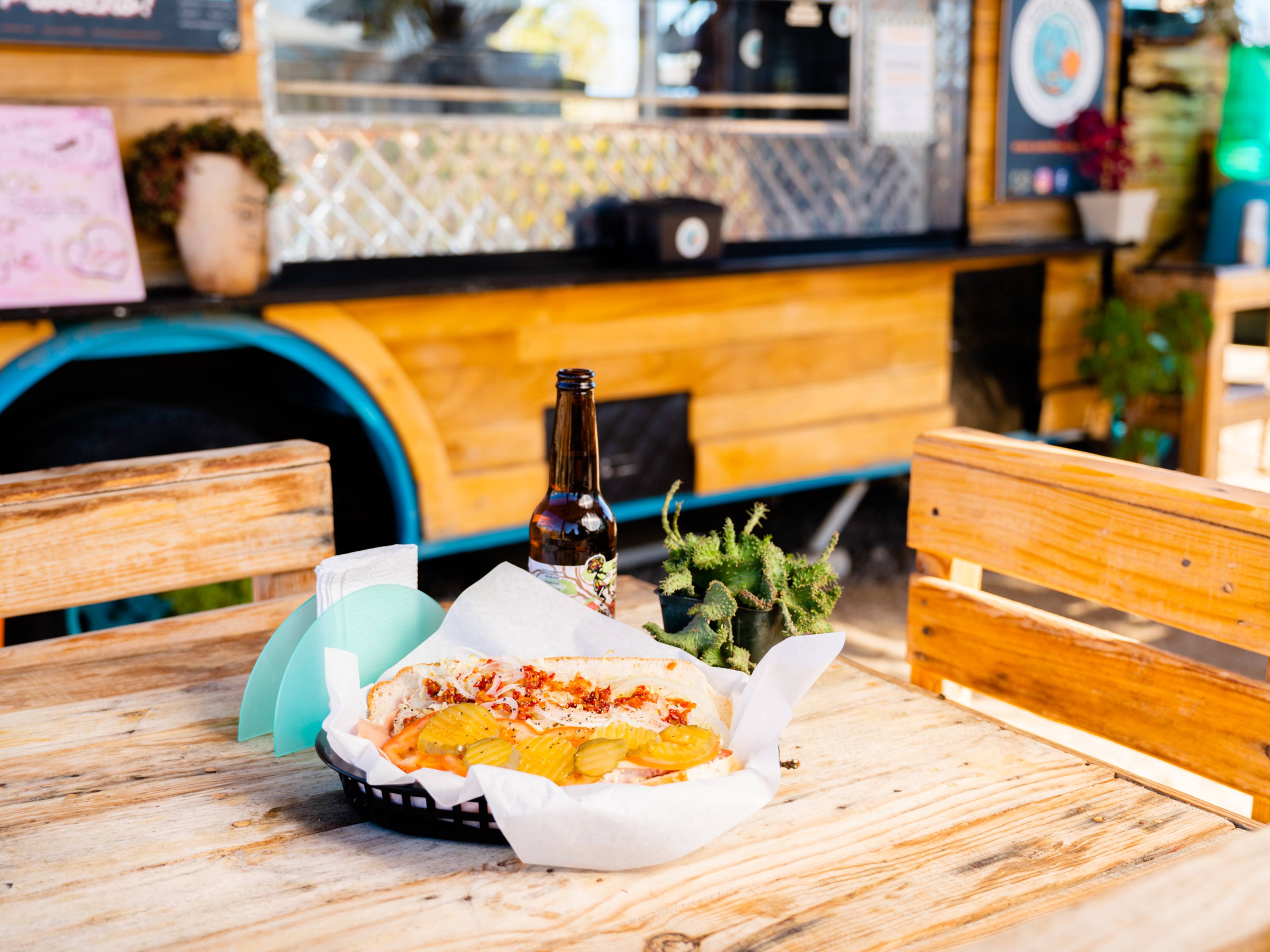 Sandwich and bottle of beer on outdoor table at Señor Hoagie