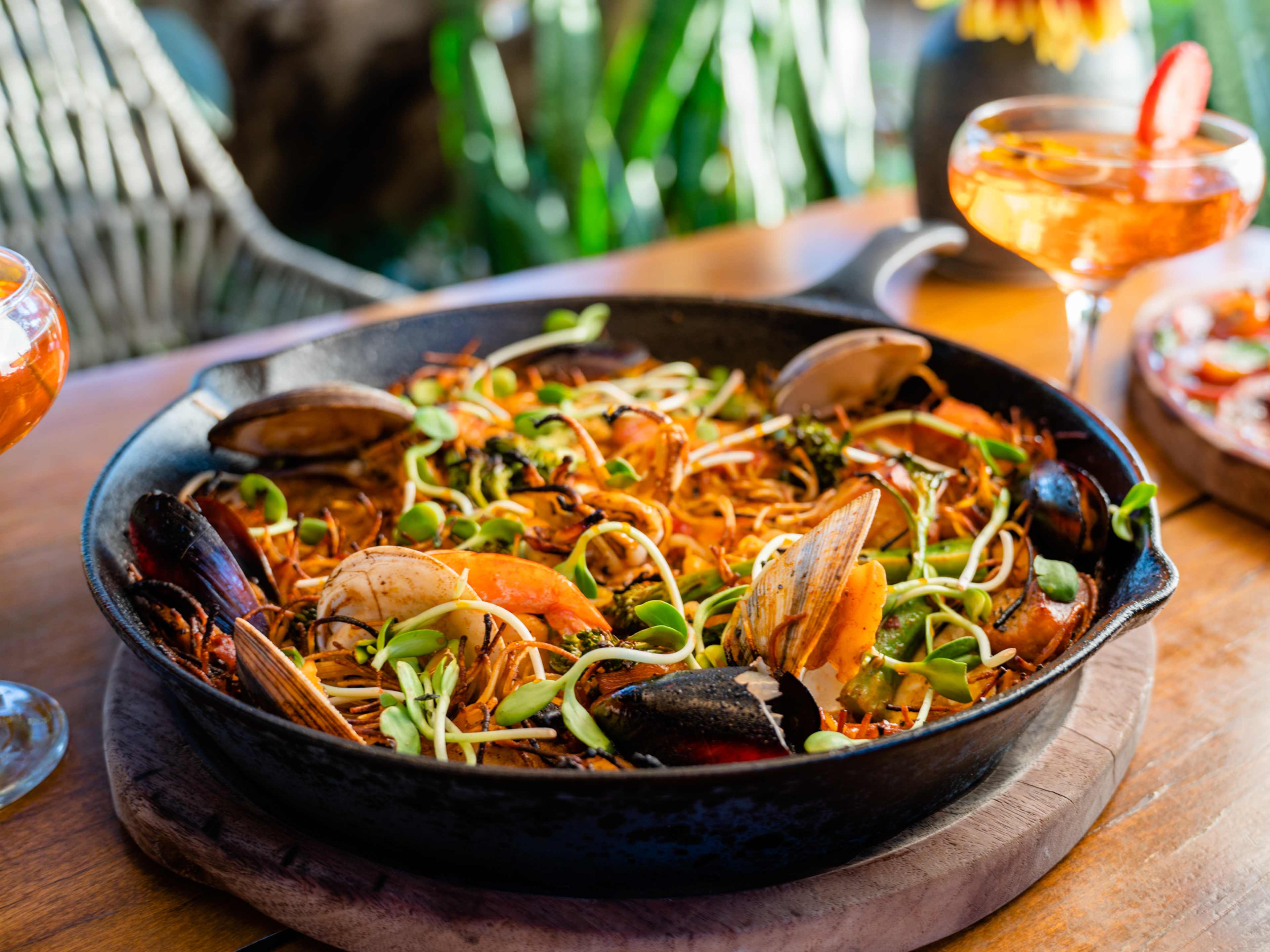 Seafood paella served in cast iron skillet at Cocina de Campo by Agricole