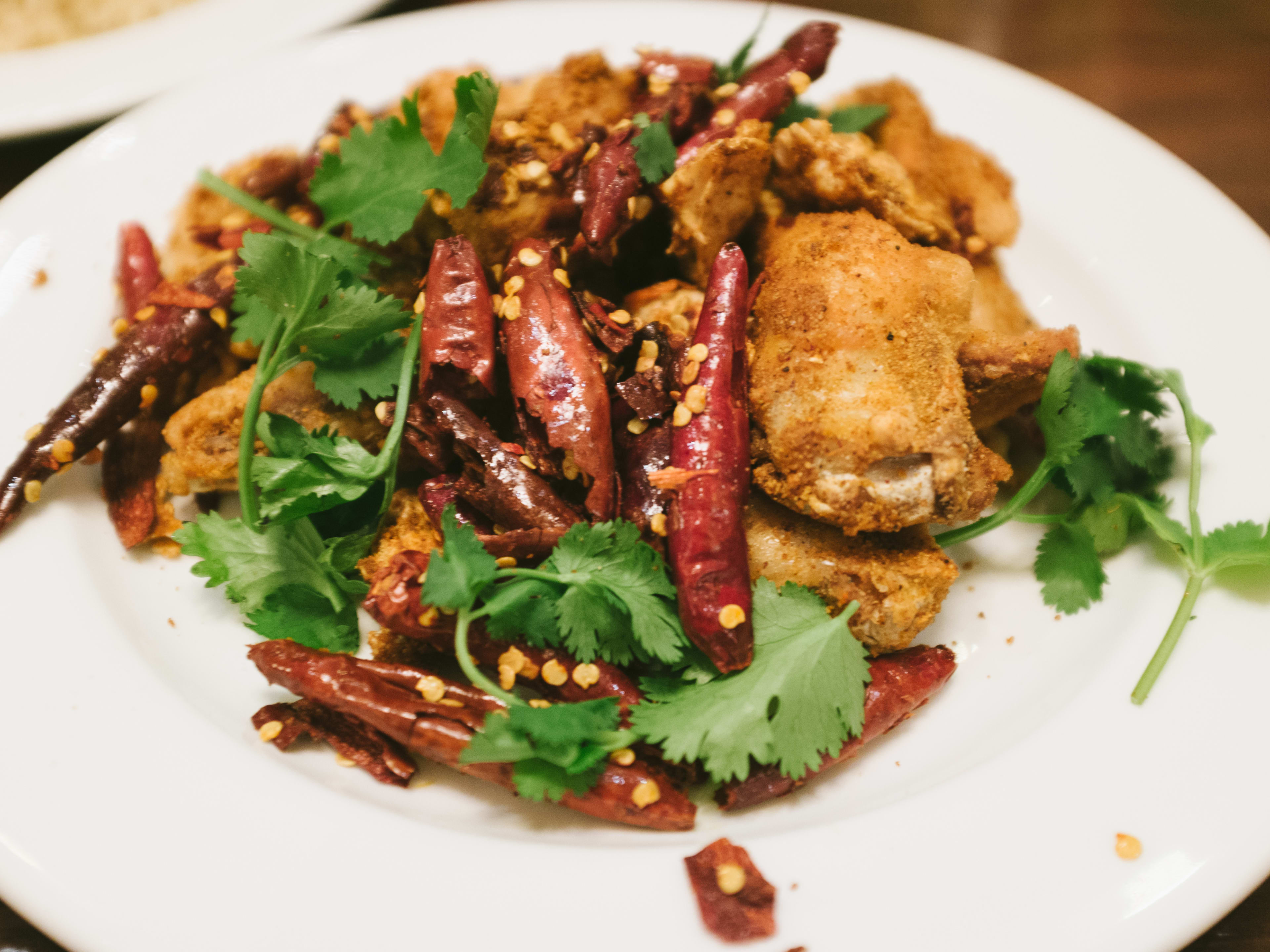 Fried chicken and red chili peppers on a white plate.