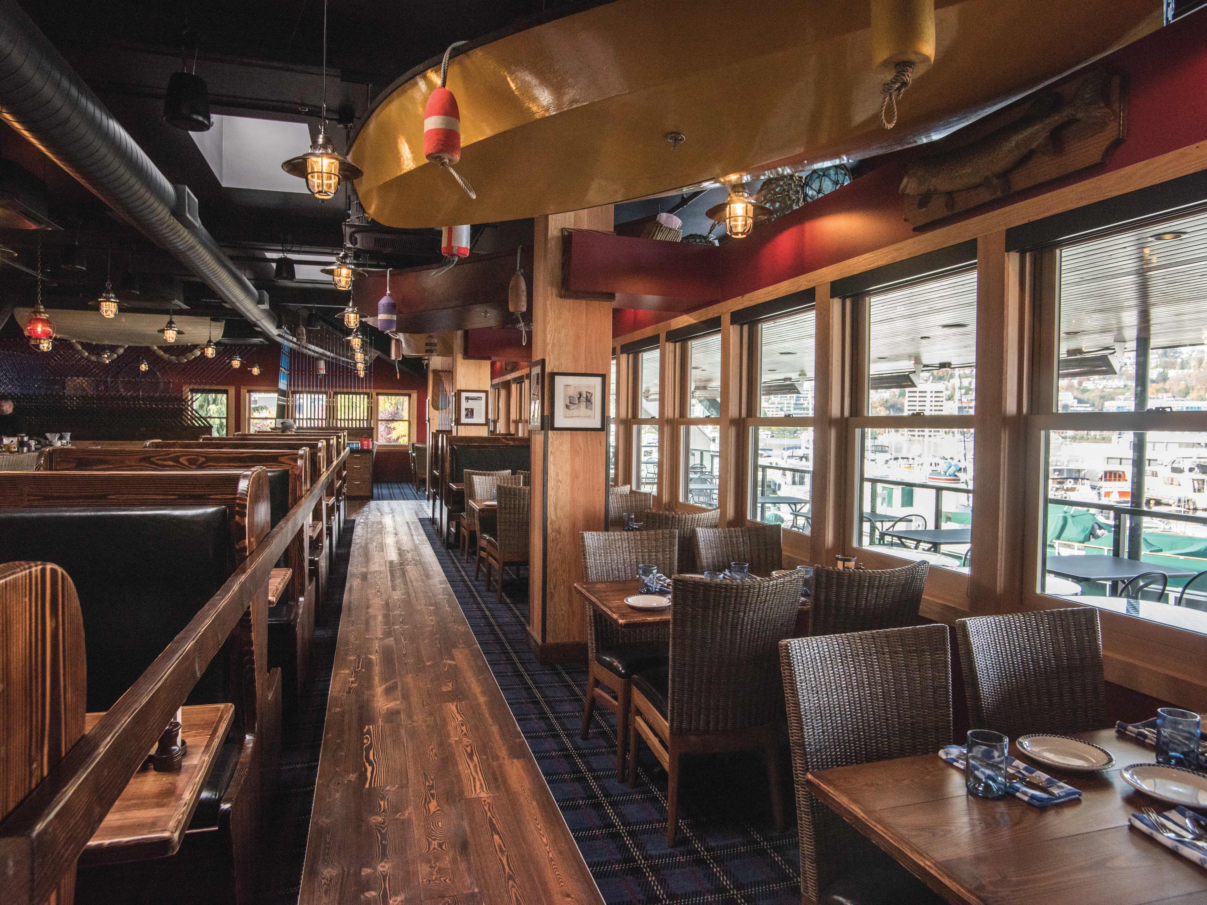 Seafood restaurant interior with hanging canoes, buoys, fish on the wall, and blue plaid carpeting.