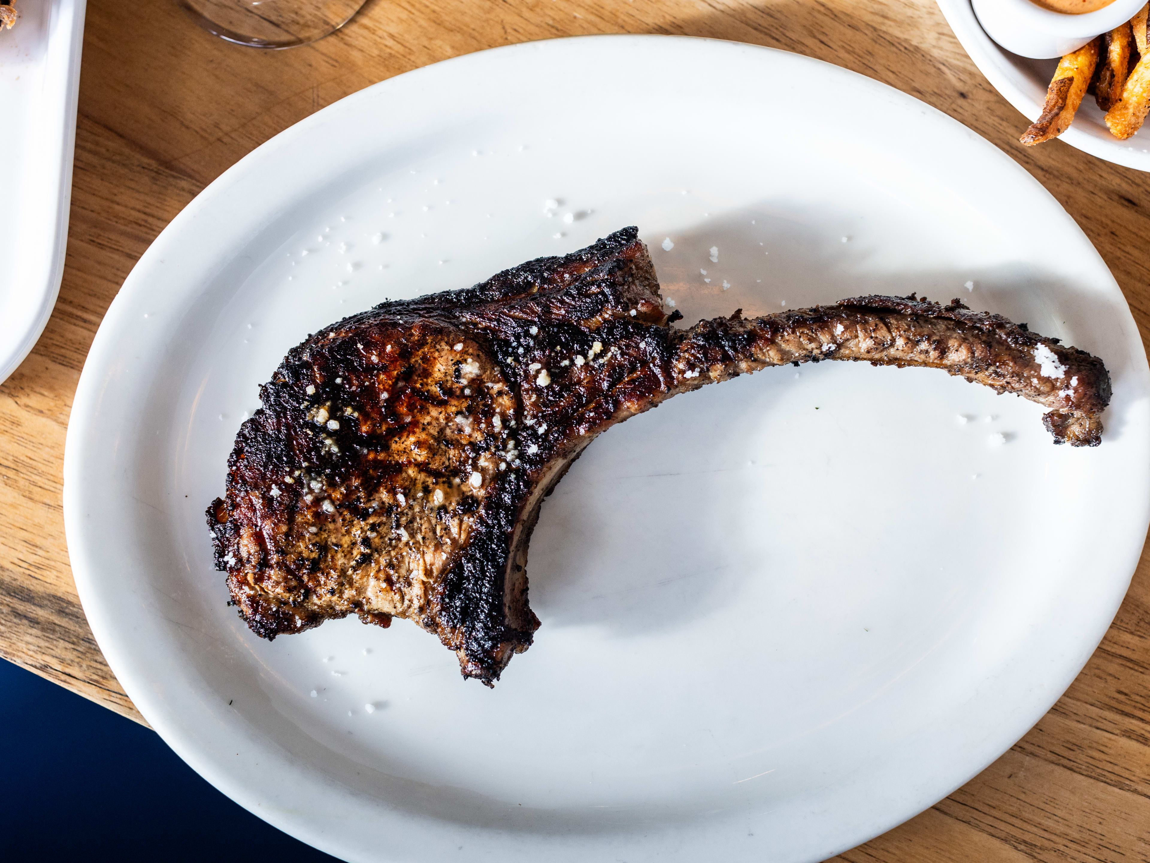 A pork chop on a white plate.