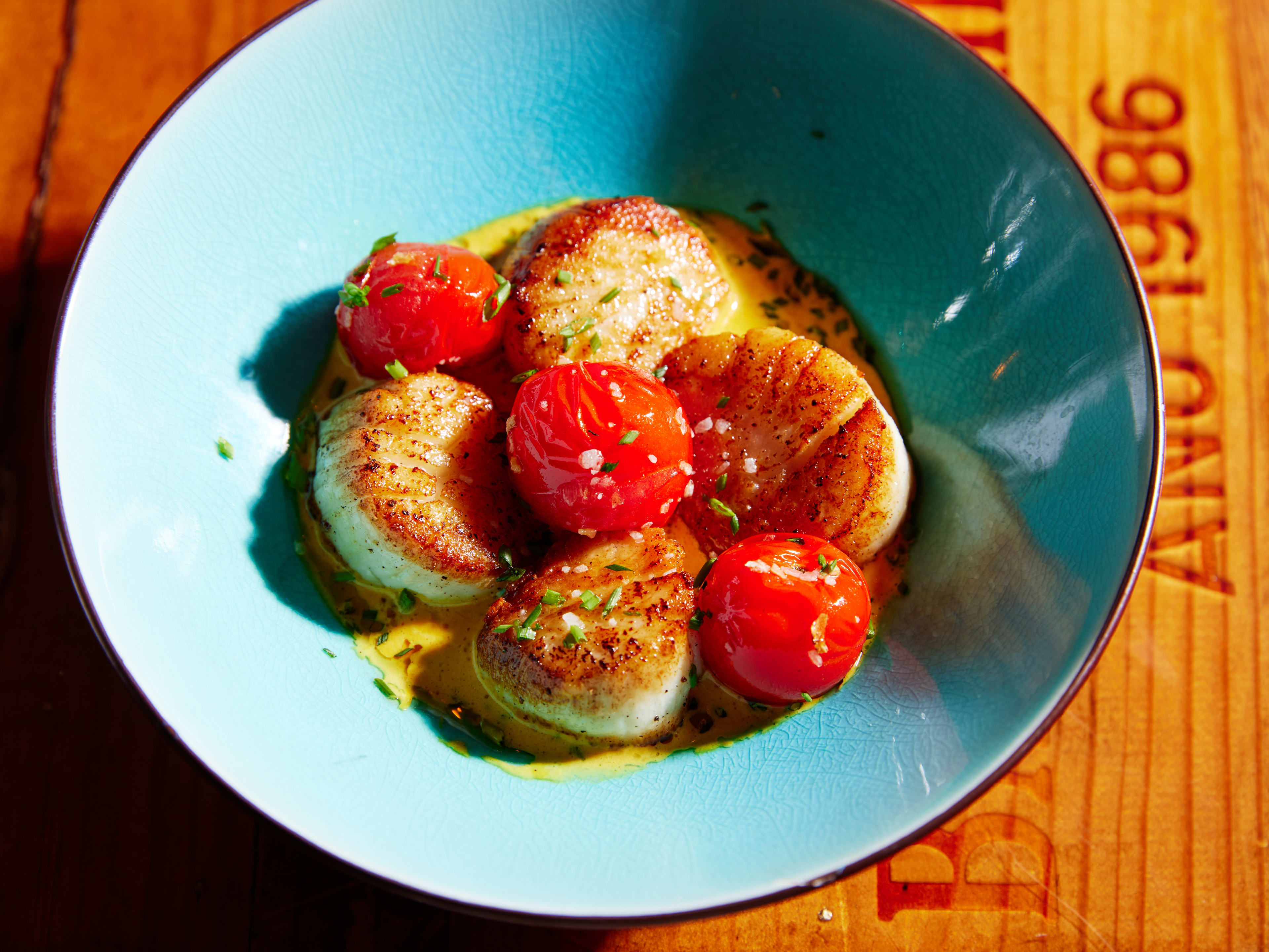 Scallop and tomato dish in blue bowl at Dali