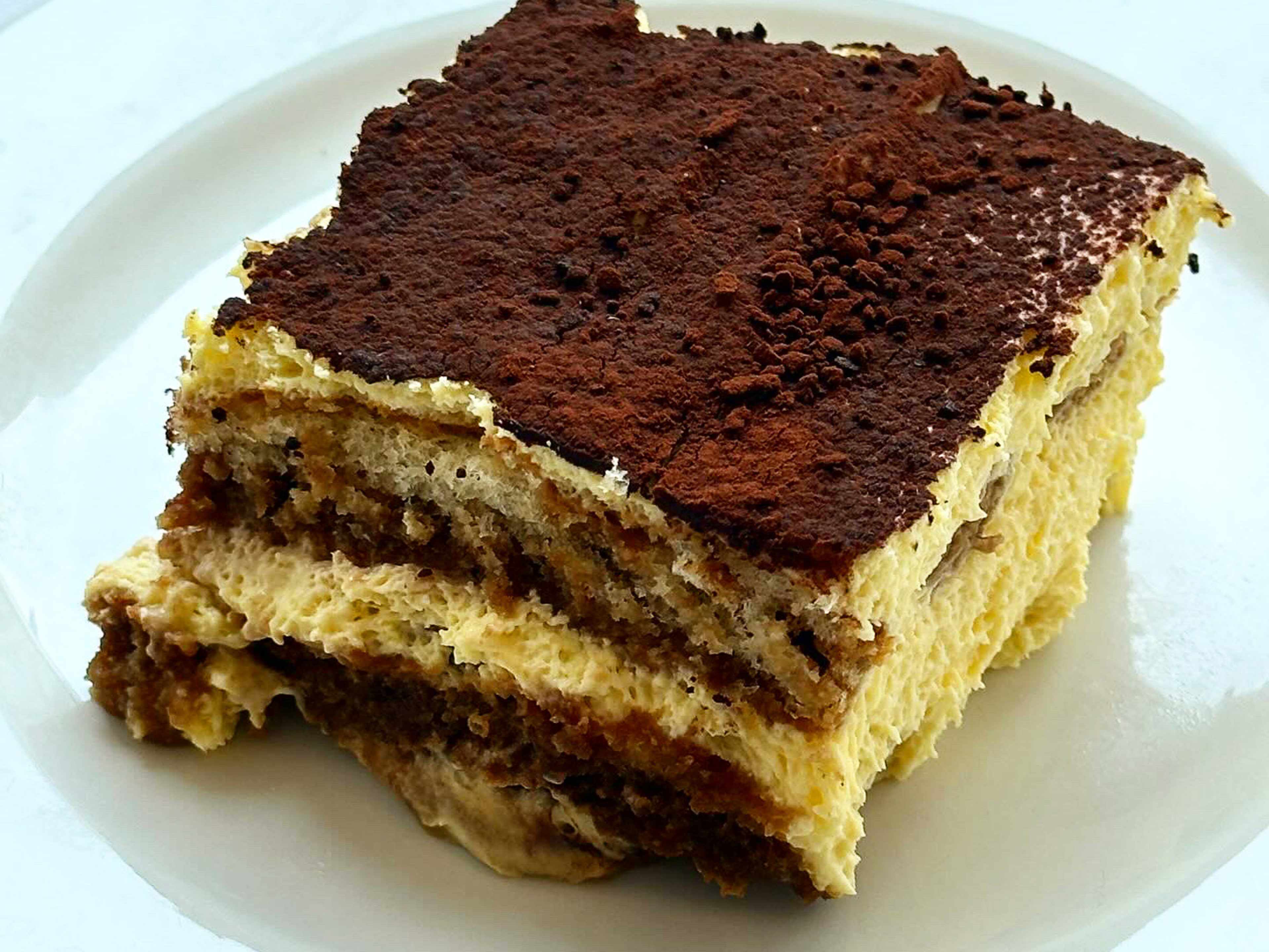 A thick slab of tiramisu on a white plate.