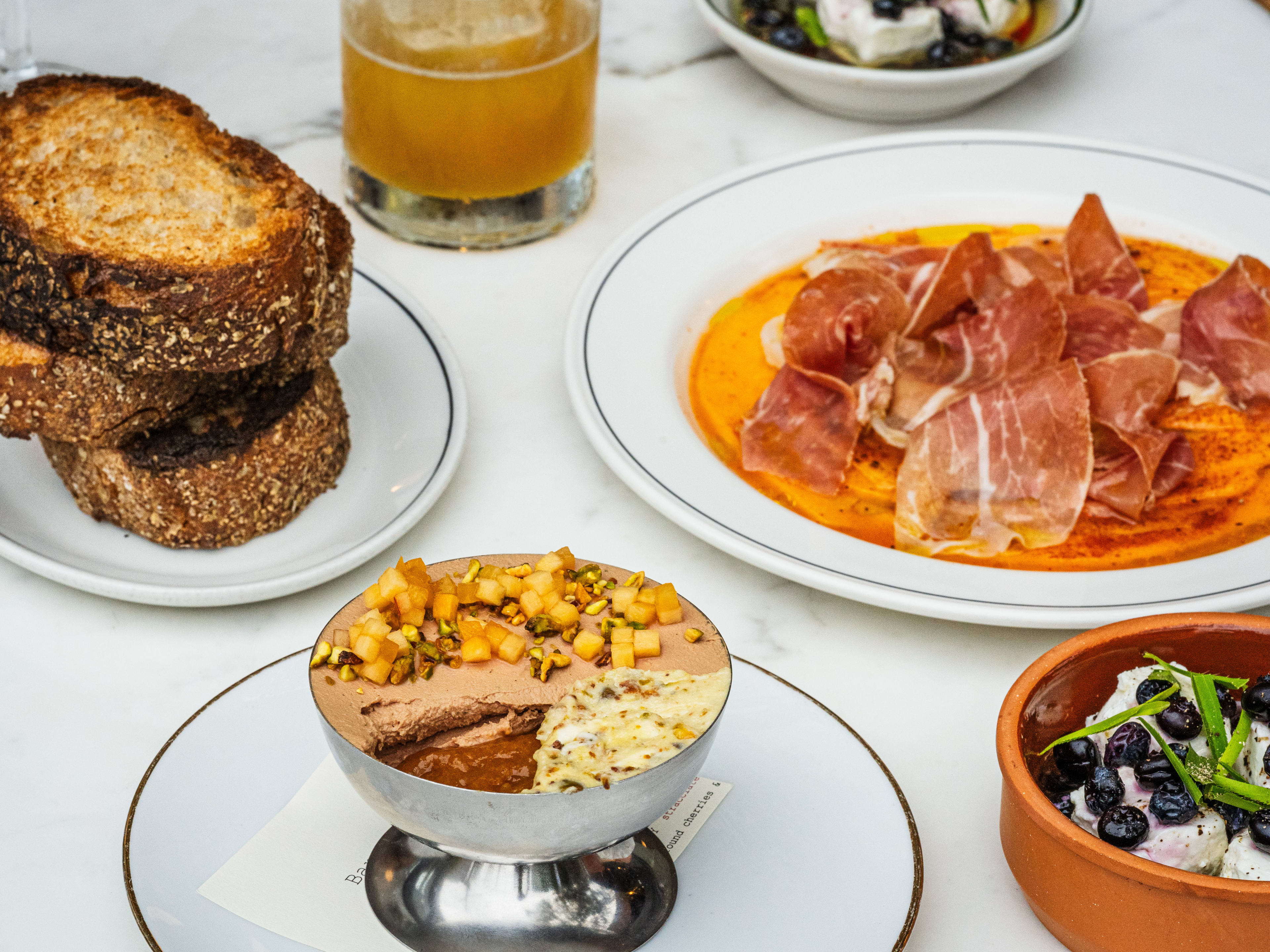 A plate of cured meat, a small pile of bread, and a chicken liver parfait.