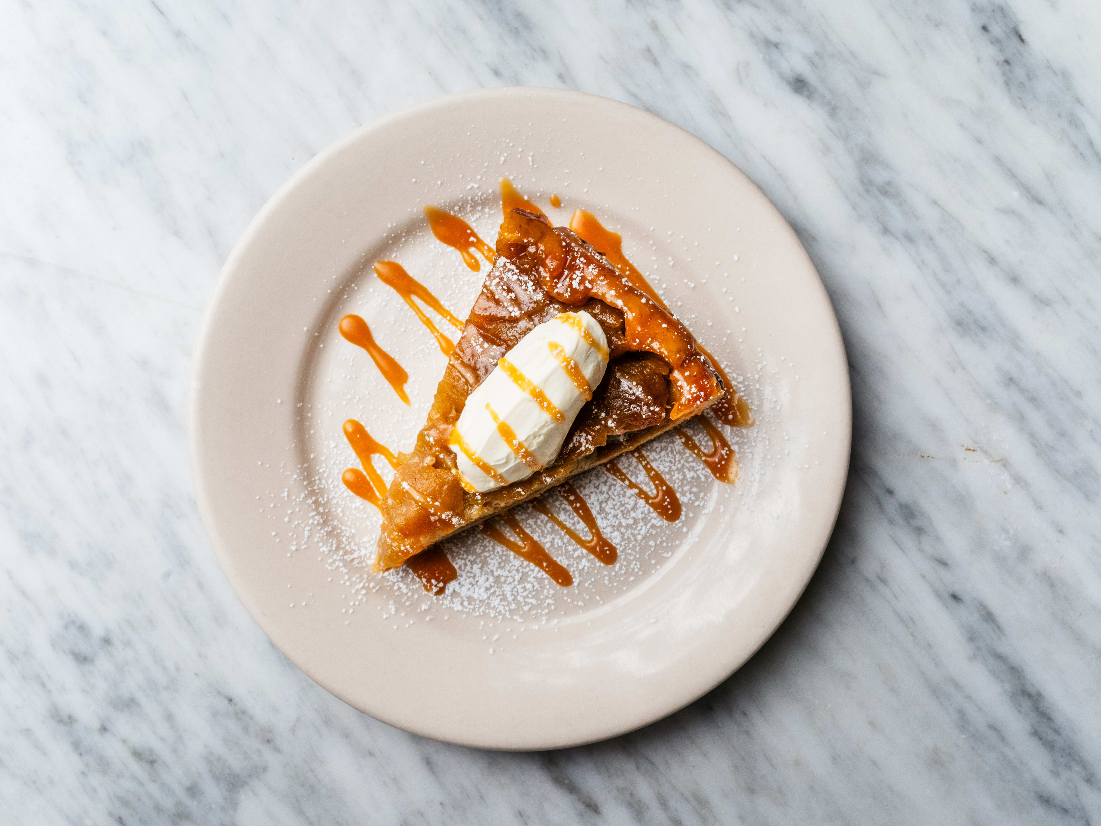 A slice of apple tart topped with ice cream.