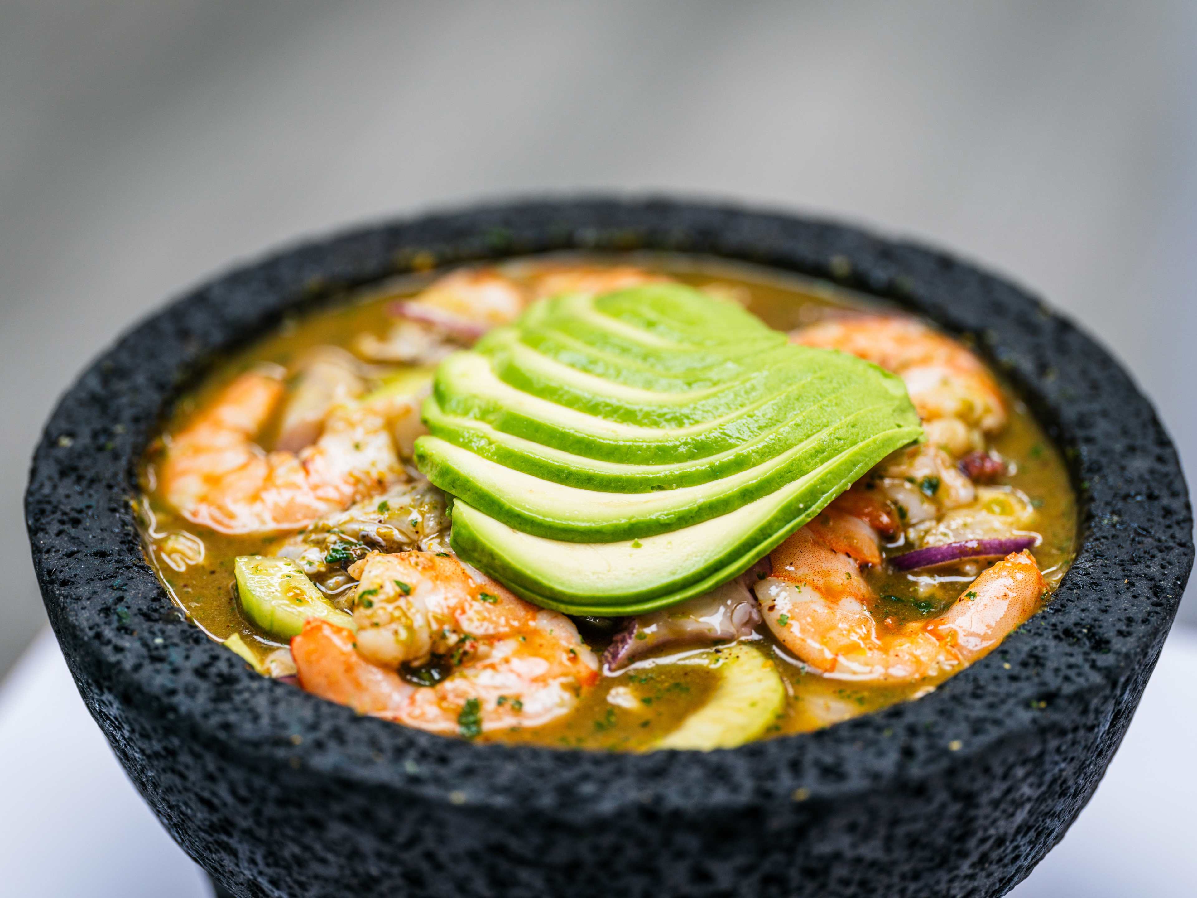 A stone bowl with aguachile negro and avocado.