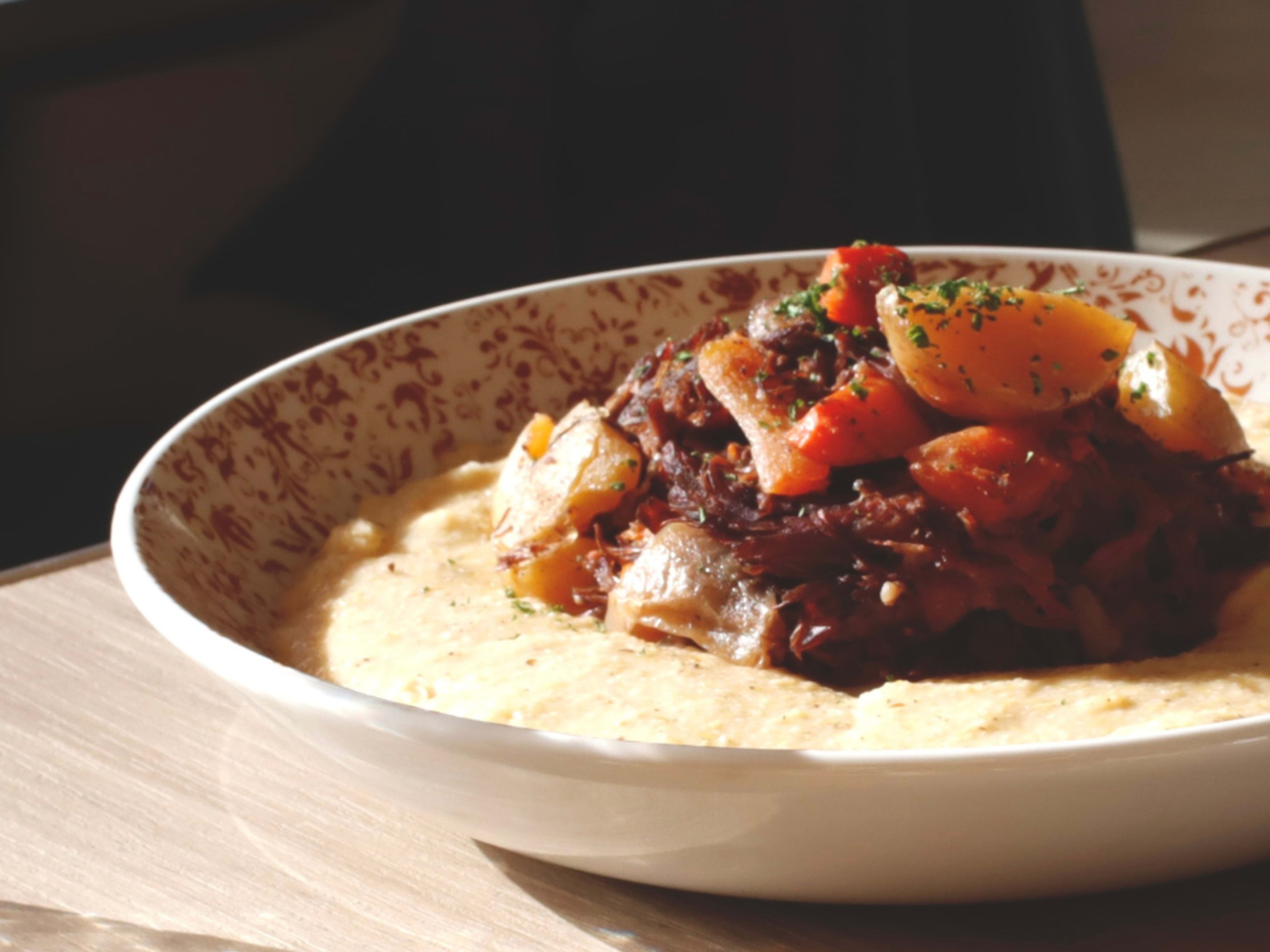 Bowl of grits topped with short rib