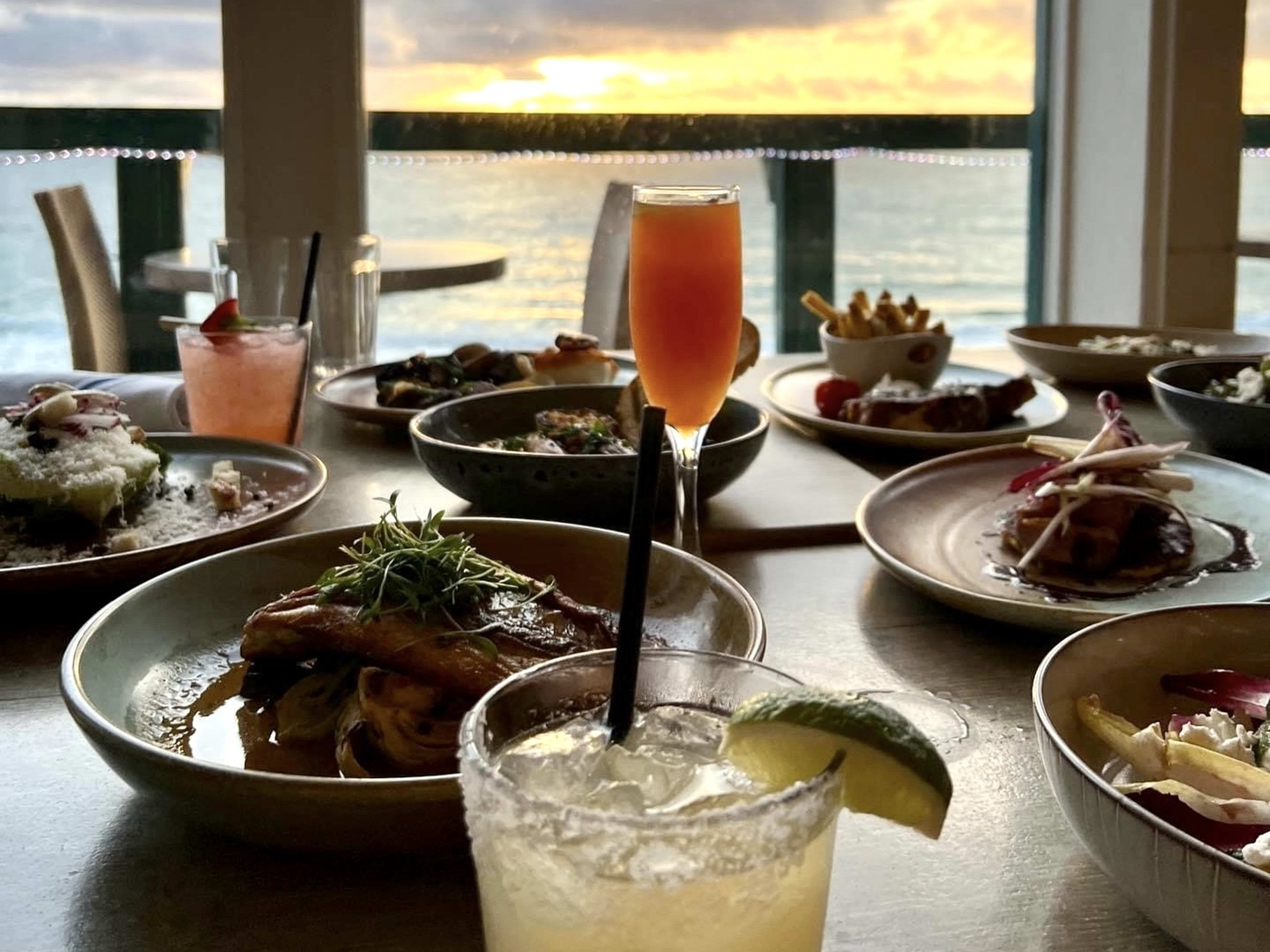 A view of the sunset over a table with food at Driftwood Kitchen