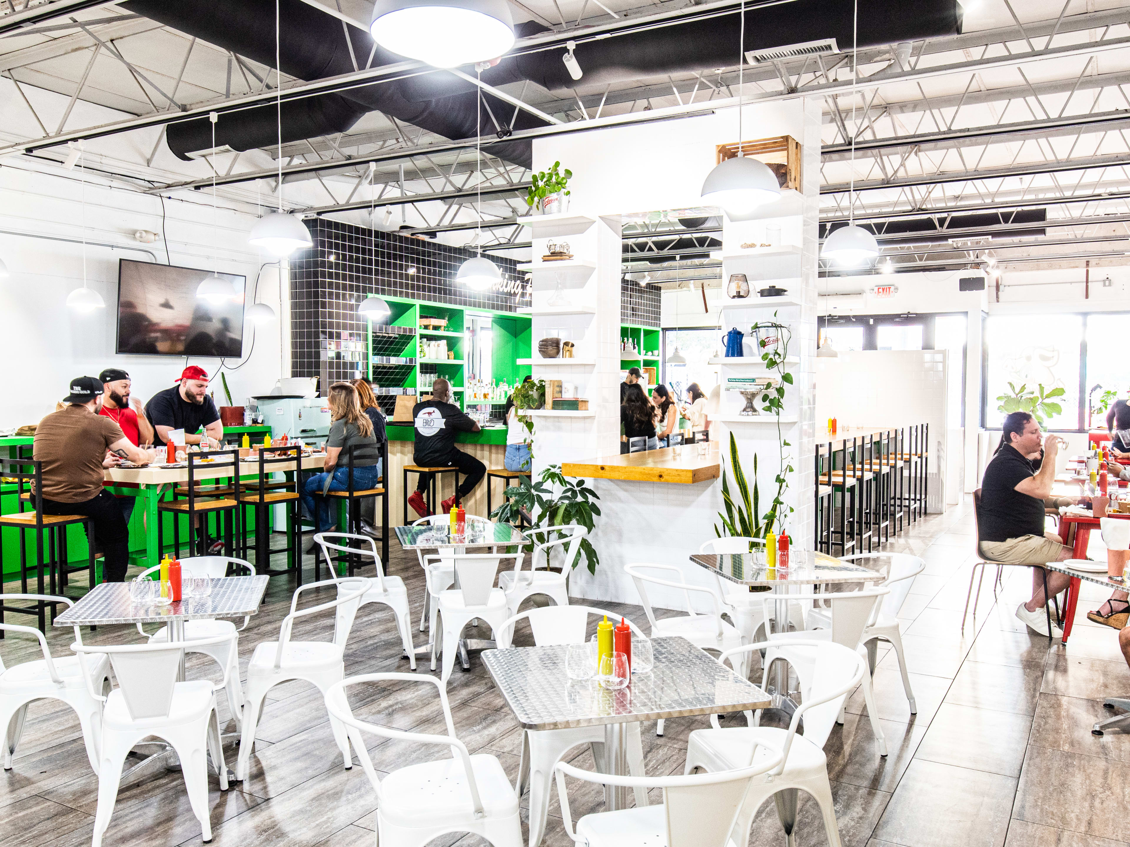 A big dining room with white tables and one long communal table.