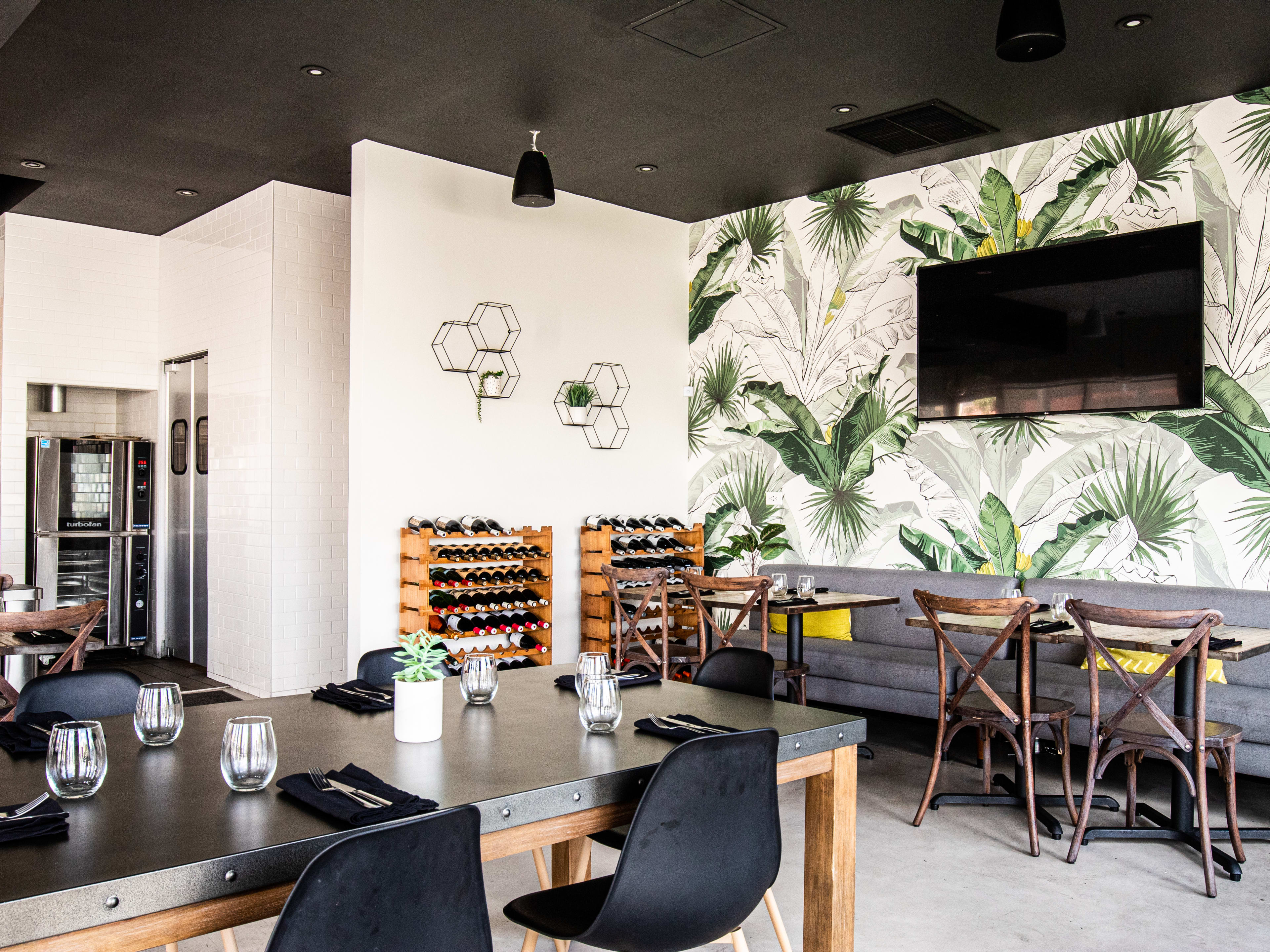 A dining room with tables, a wine rack, and a TV.