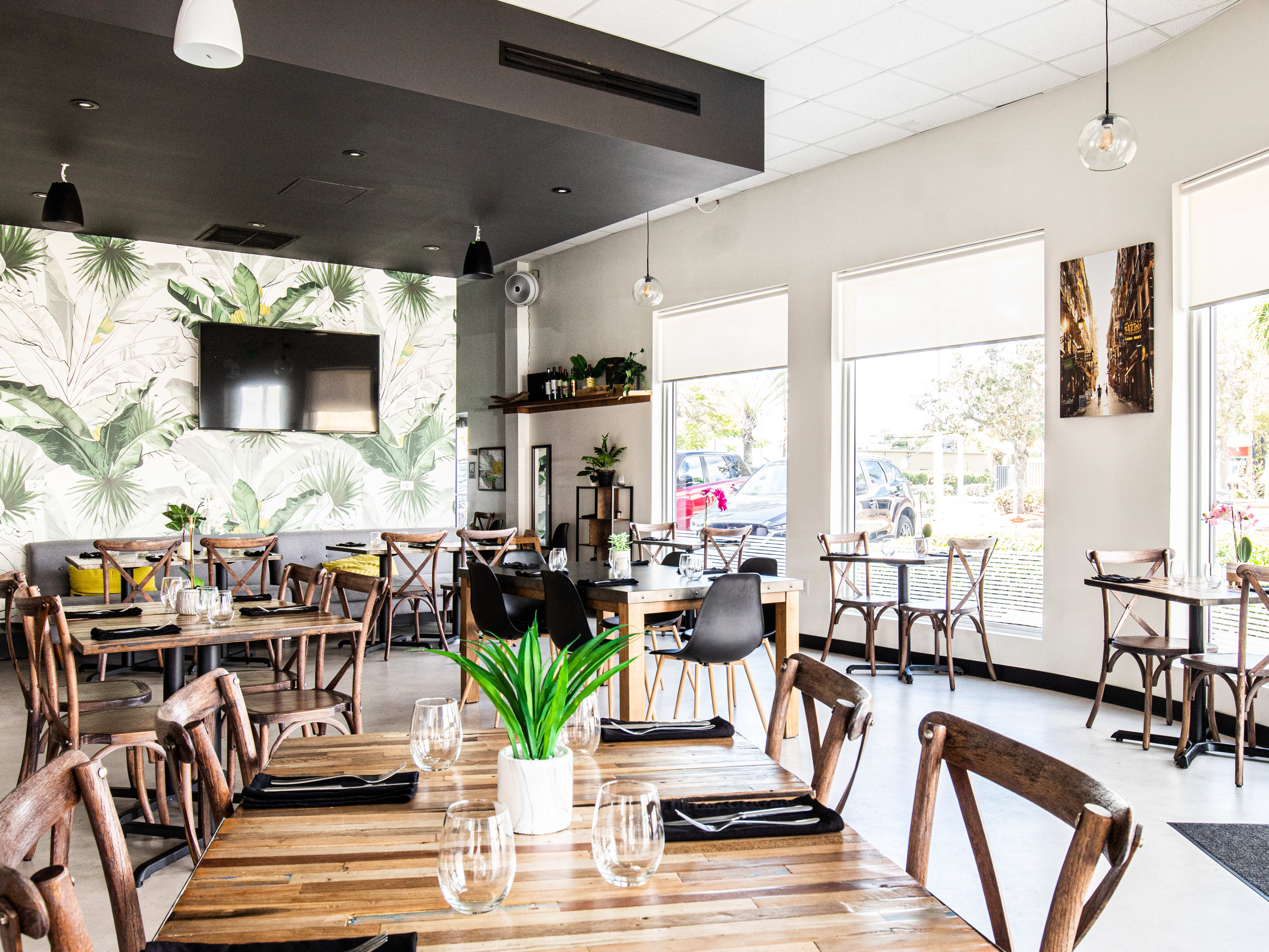 A bright and empty dining room with a dozen tables and big windows.