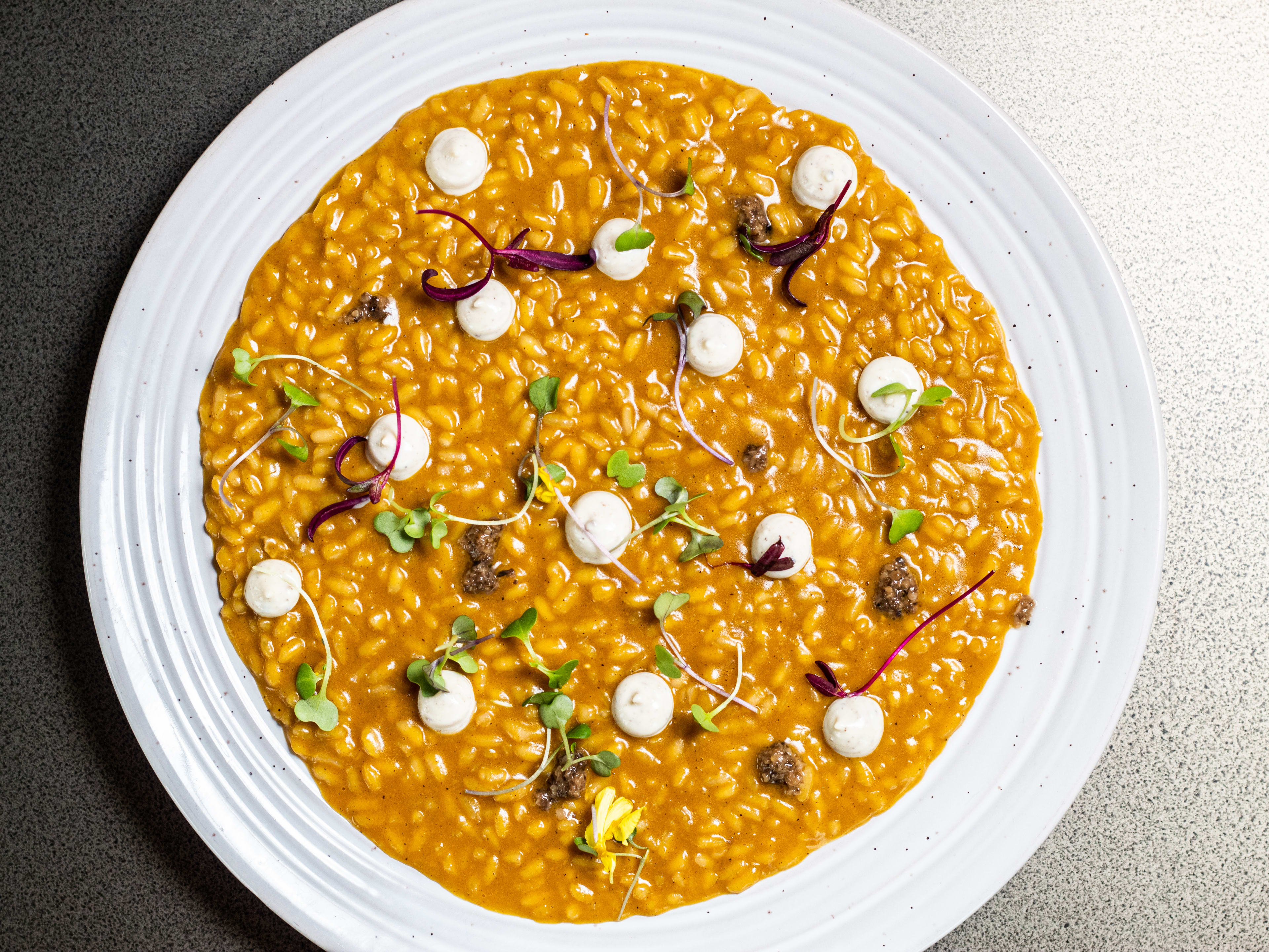 A plate of pumpkin rice with dollops of white sauce.