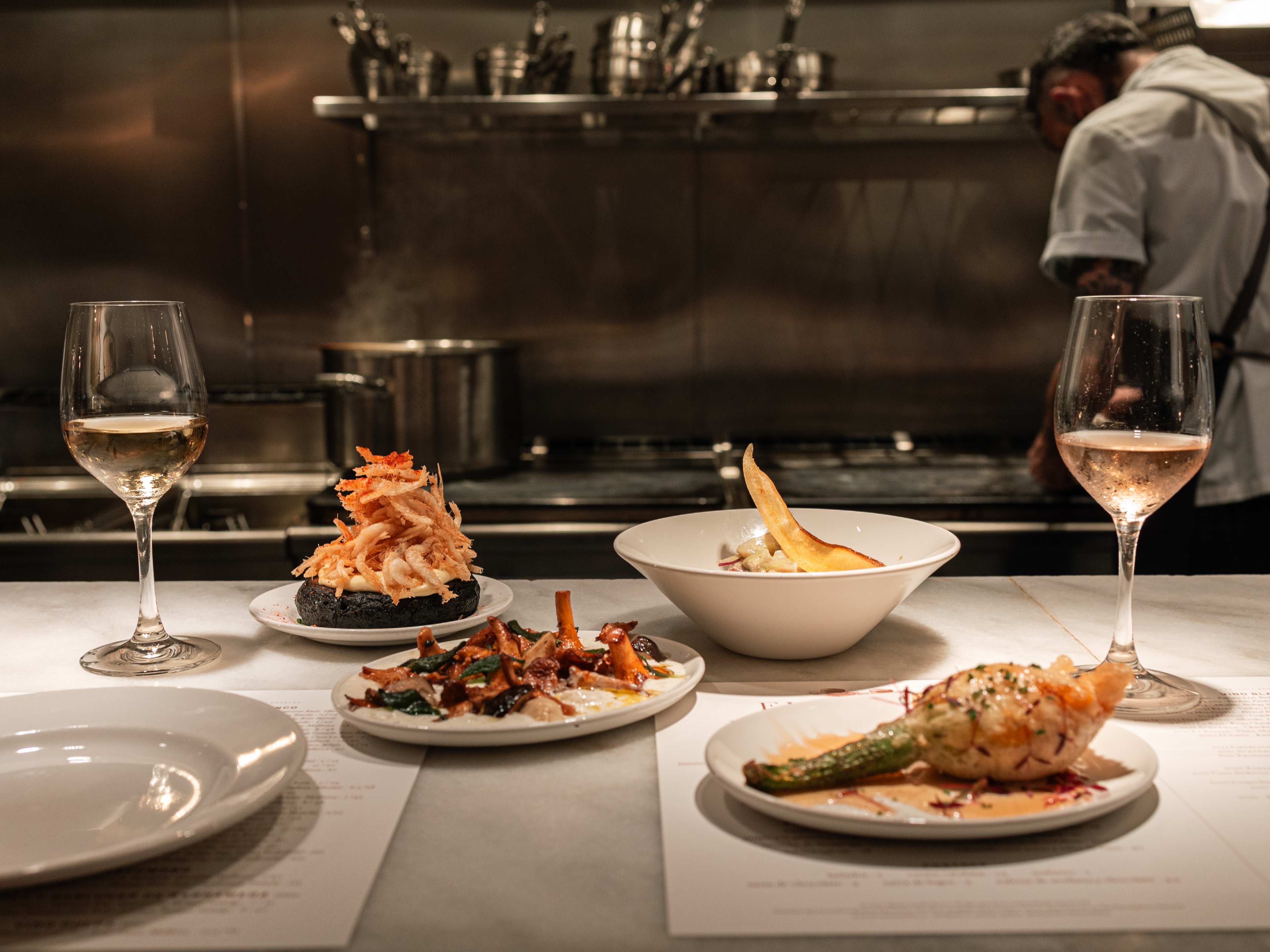 spread of tapas and wine at bar looking into open kitchen