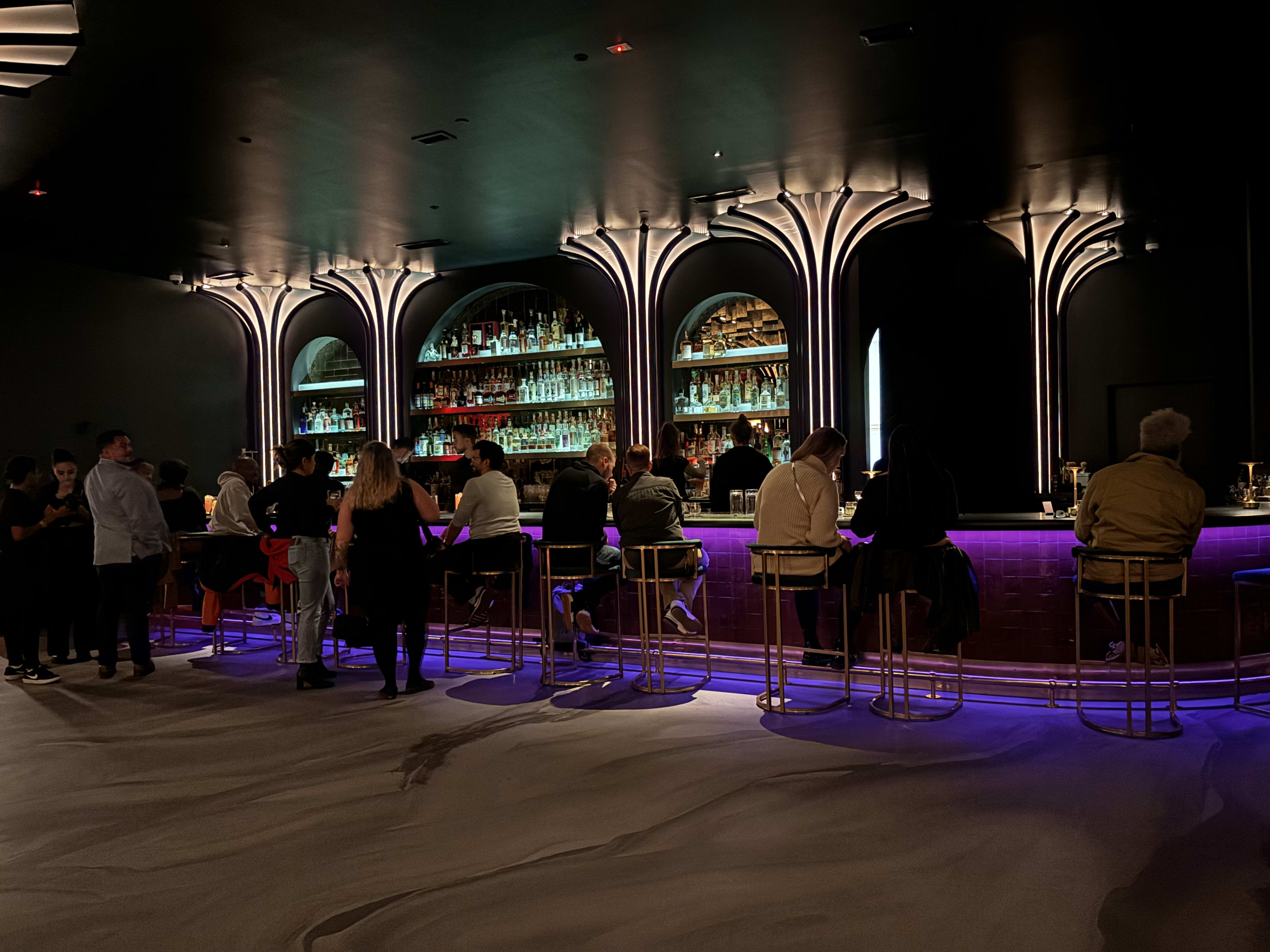 A neon-lit bar with people drinking at El Malo in Atlanta.