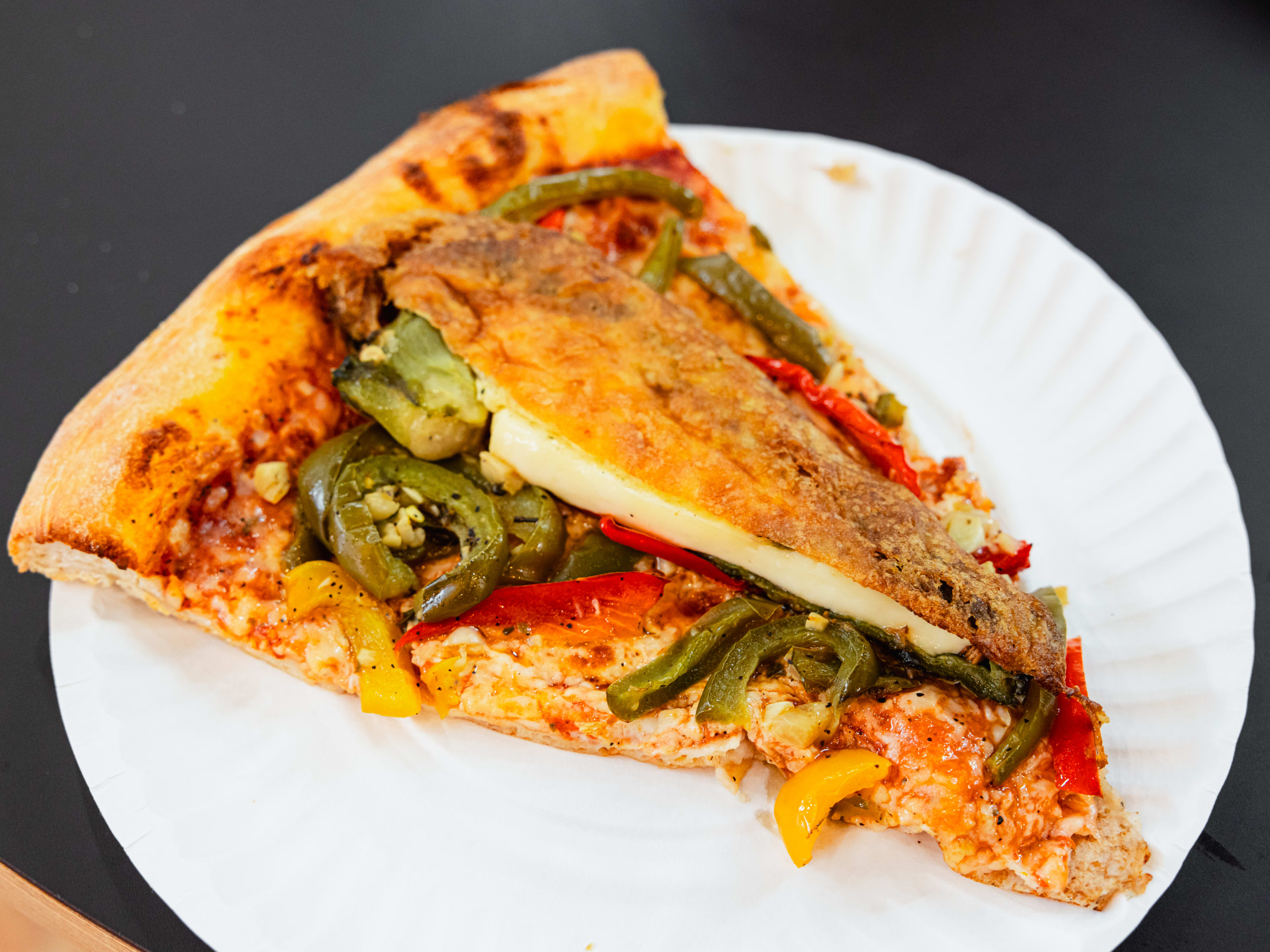 A slice of pizza with a chile relleno on top.