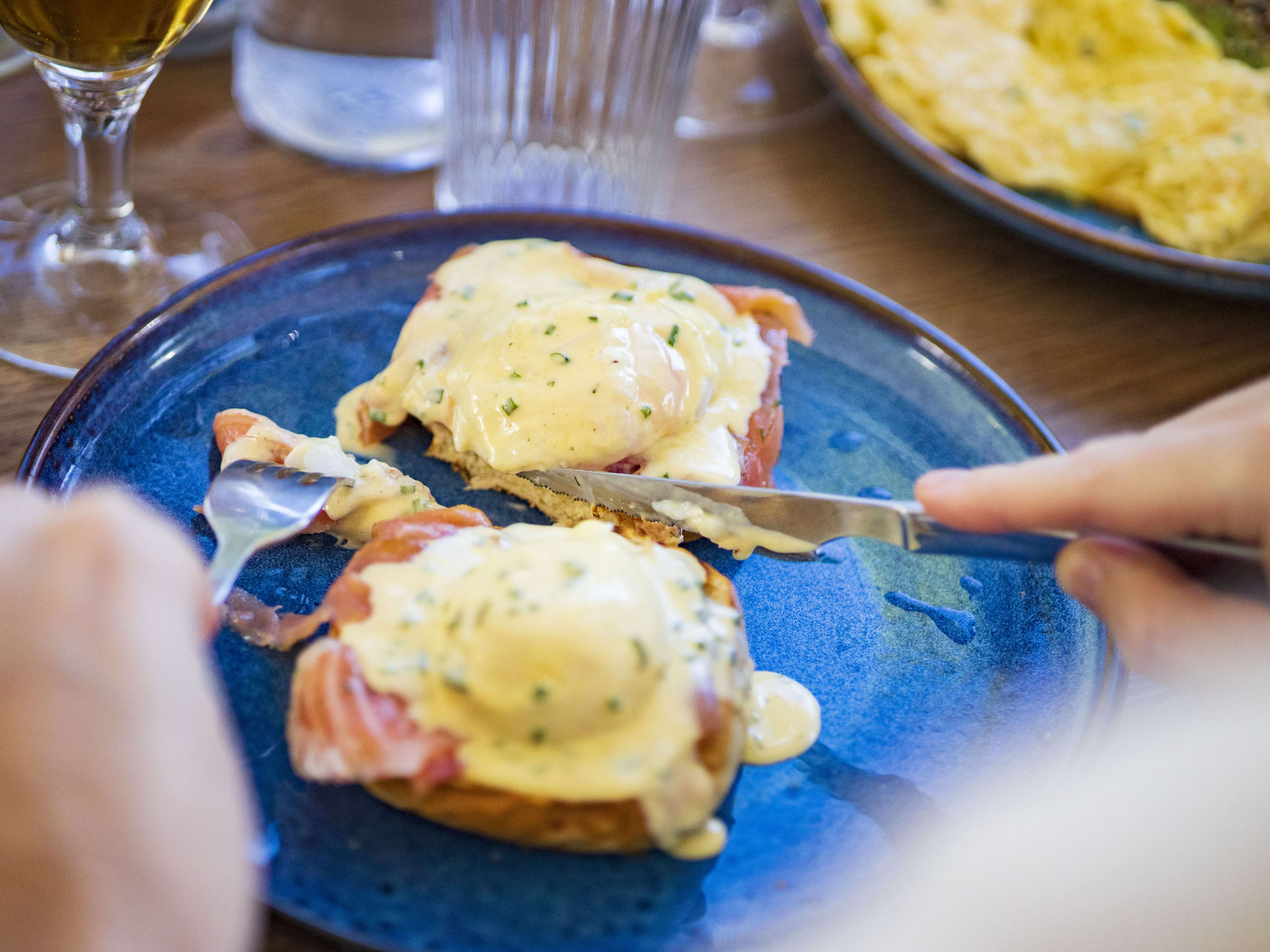 person cutting into eggs benedict