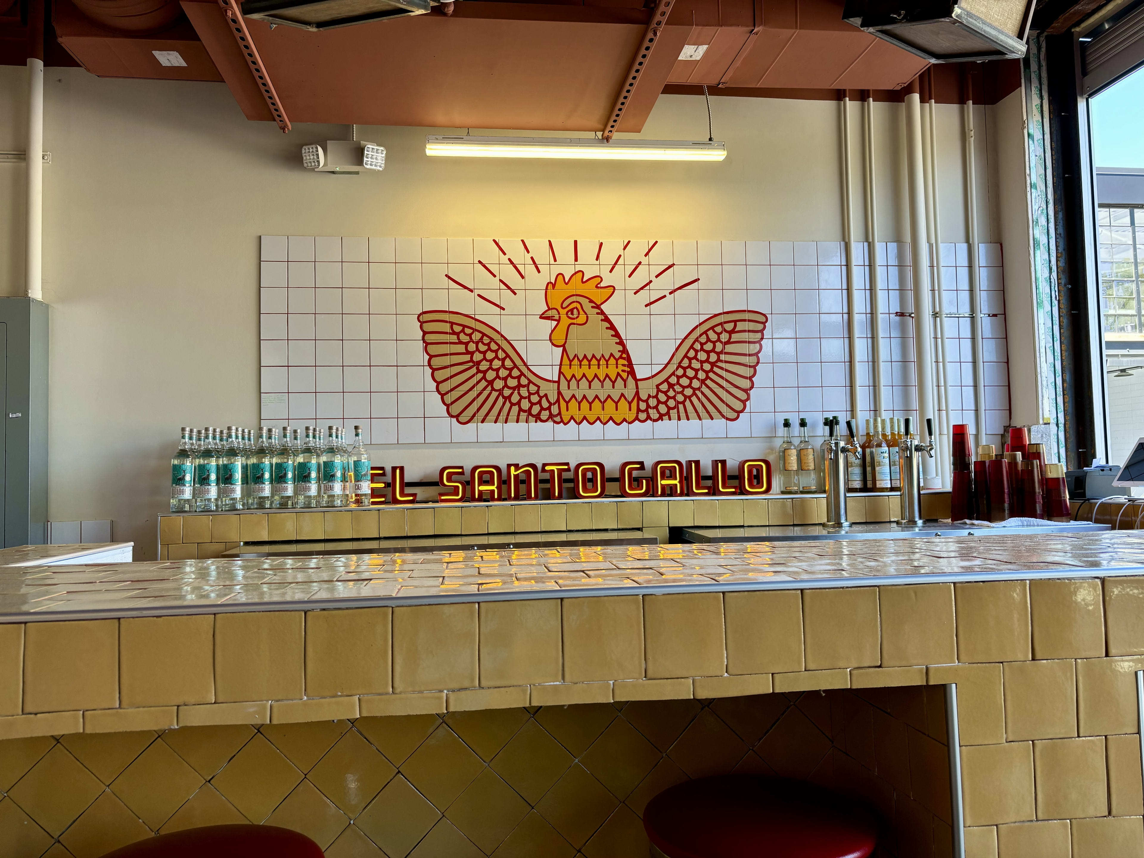 A red rooster with wings outstretched behind a bar.