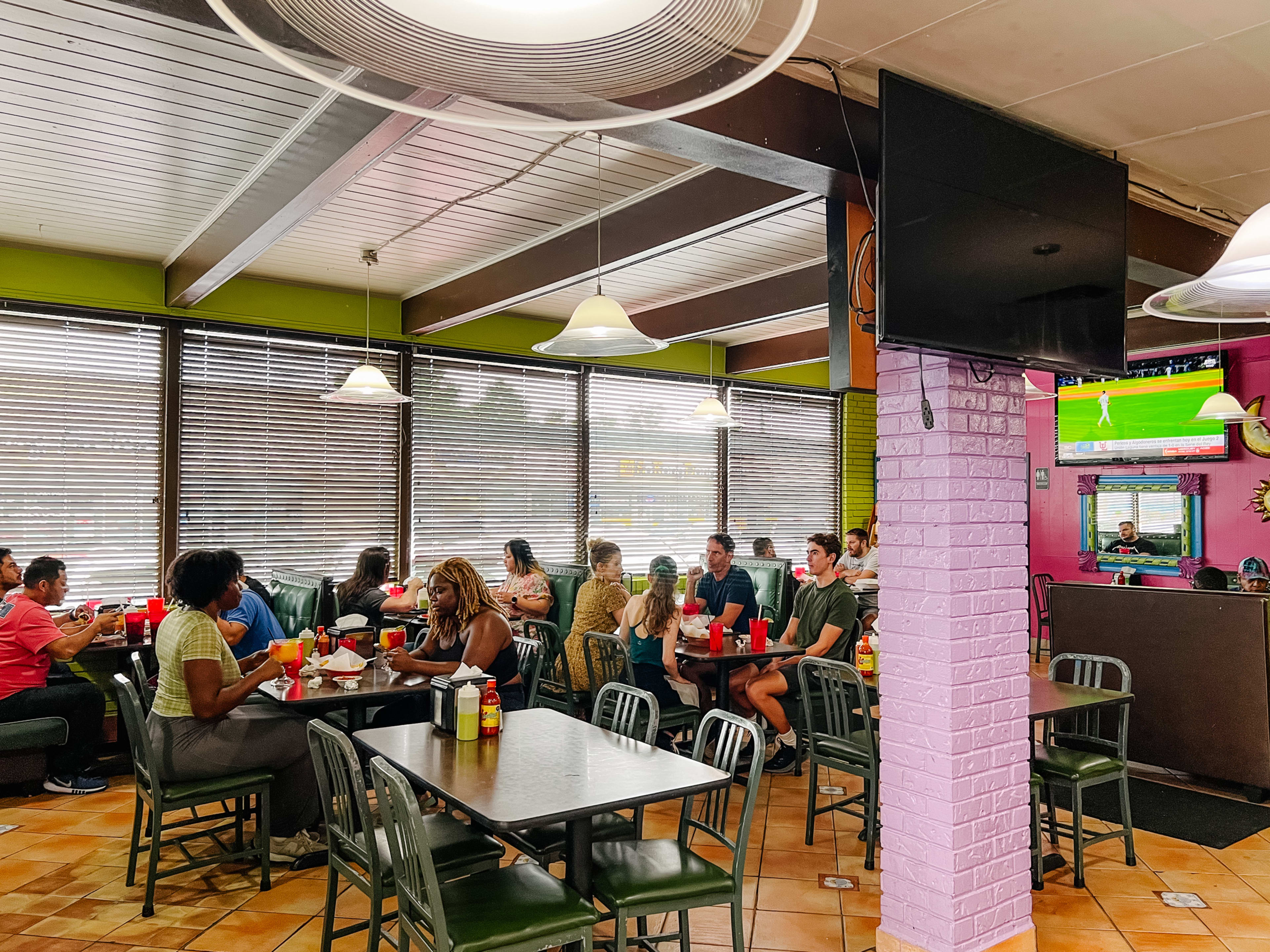 packed taco shop interior with soccer game on tv and tables full of diners