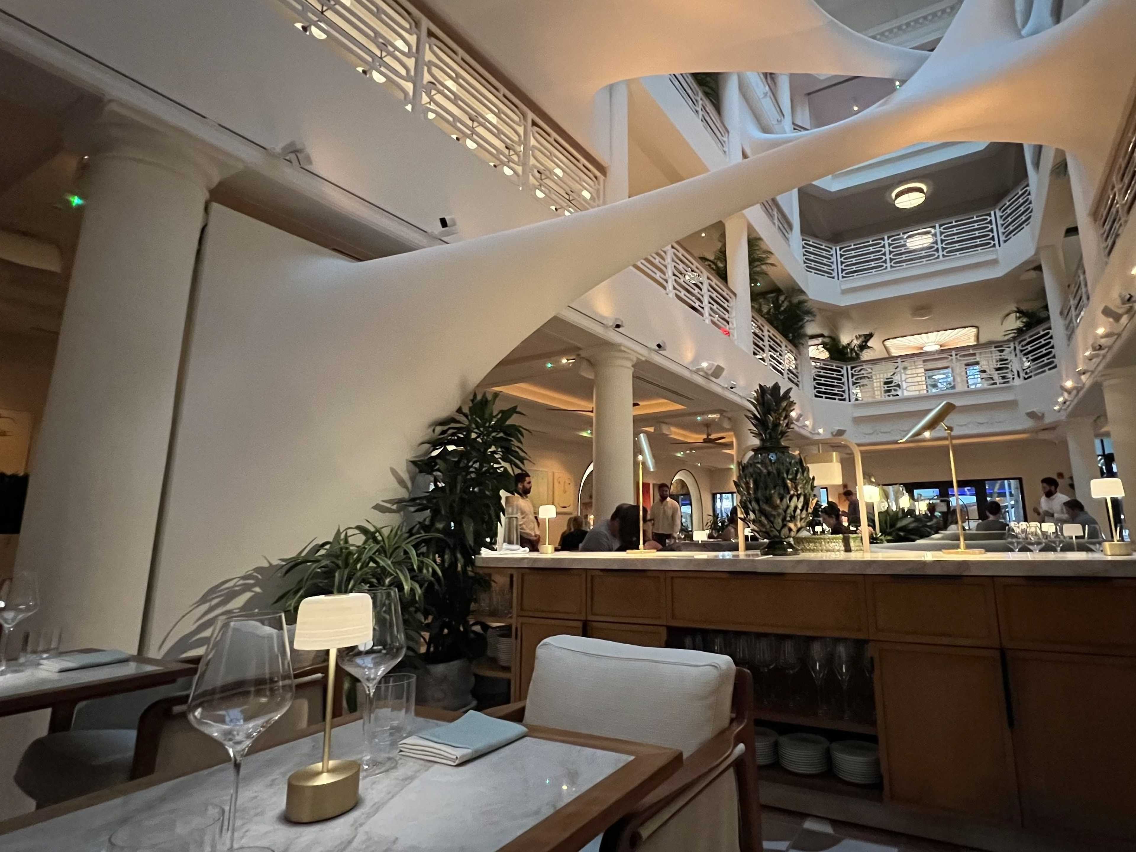 A big dining room with tall ceilings and a unique installation overhead.