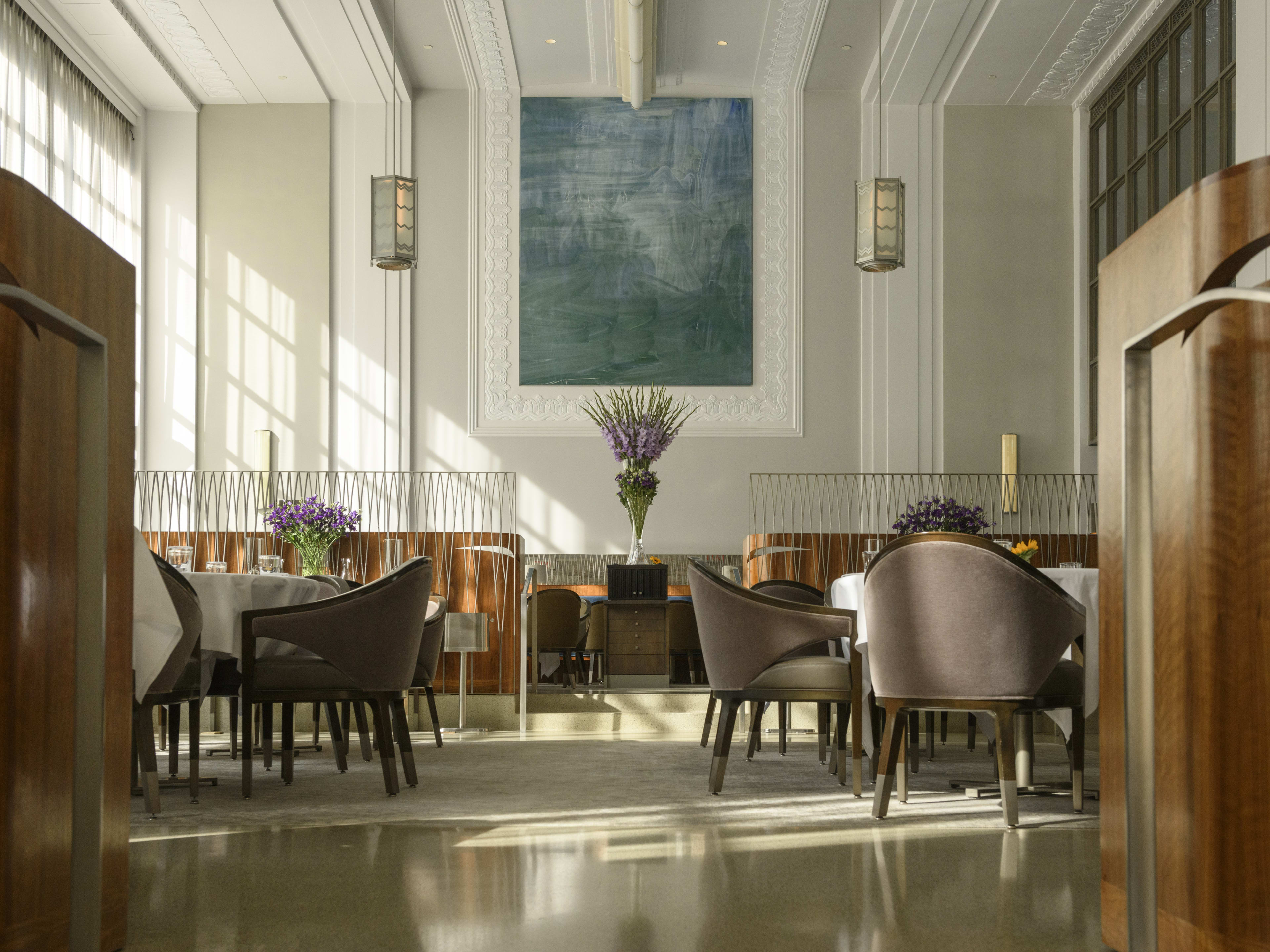 A stately dining room with high ceilings and brown chairs.