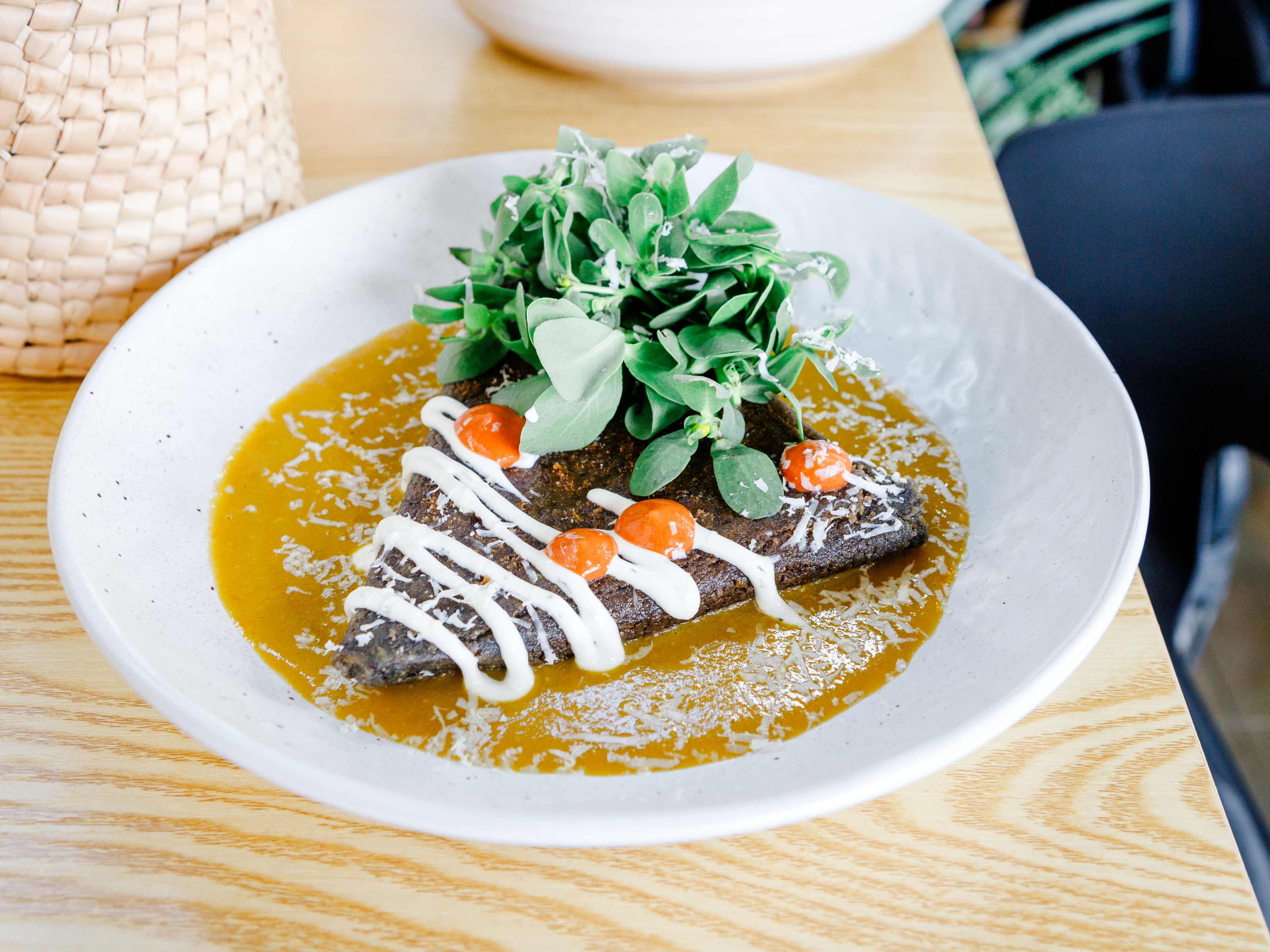 triangular mushroom tetela at Ema surrounded by salsa verda topped with purslane salad