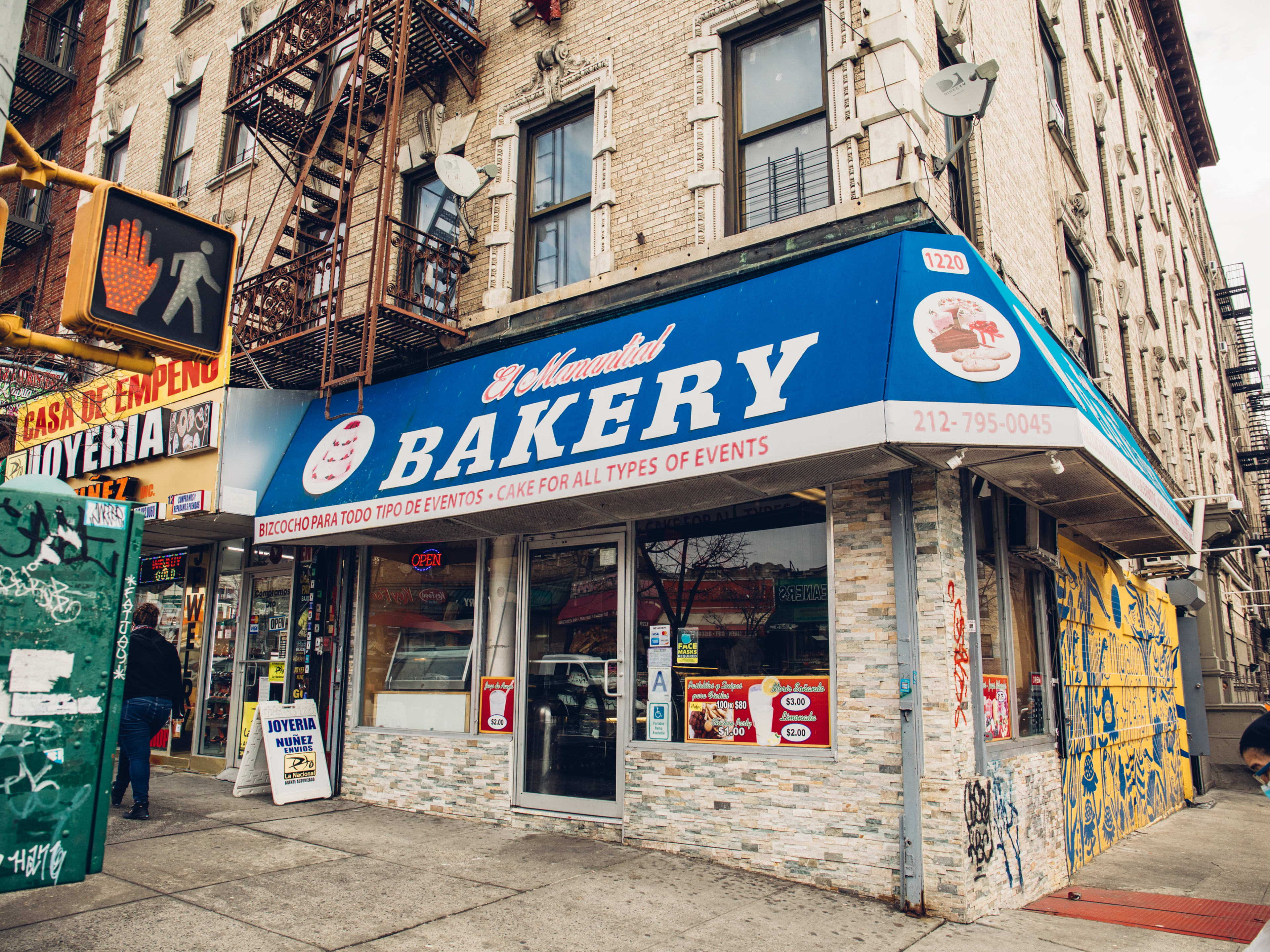 The exterior of a bakery with a big blue awning.