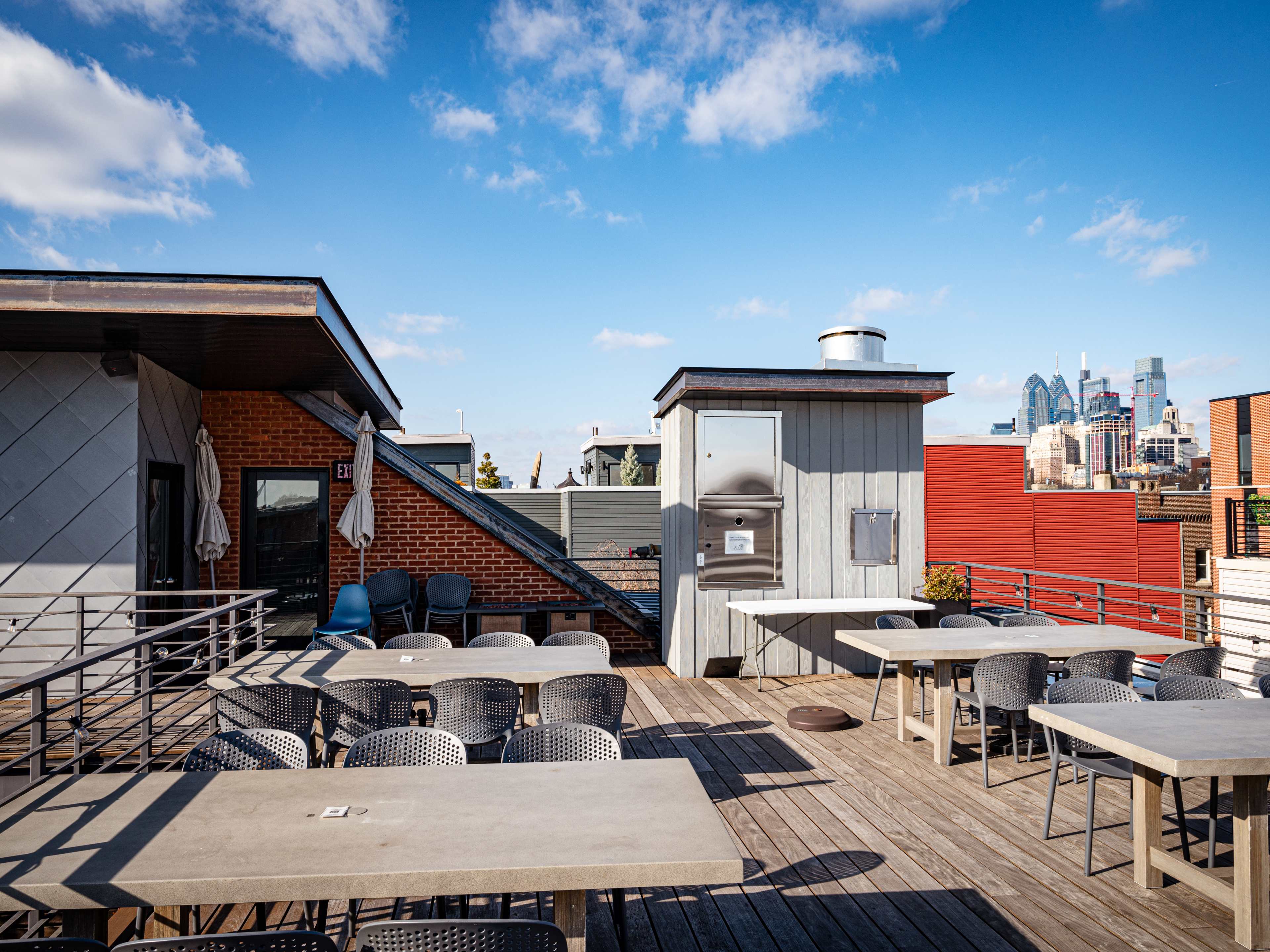 rooftop patio with tables and chairs overlooking philly skyline