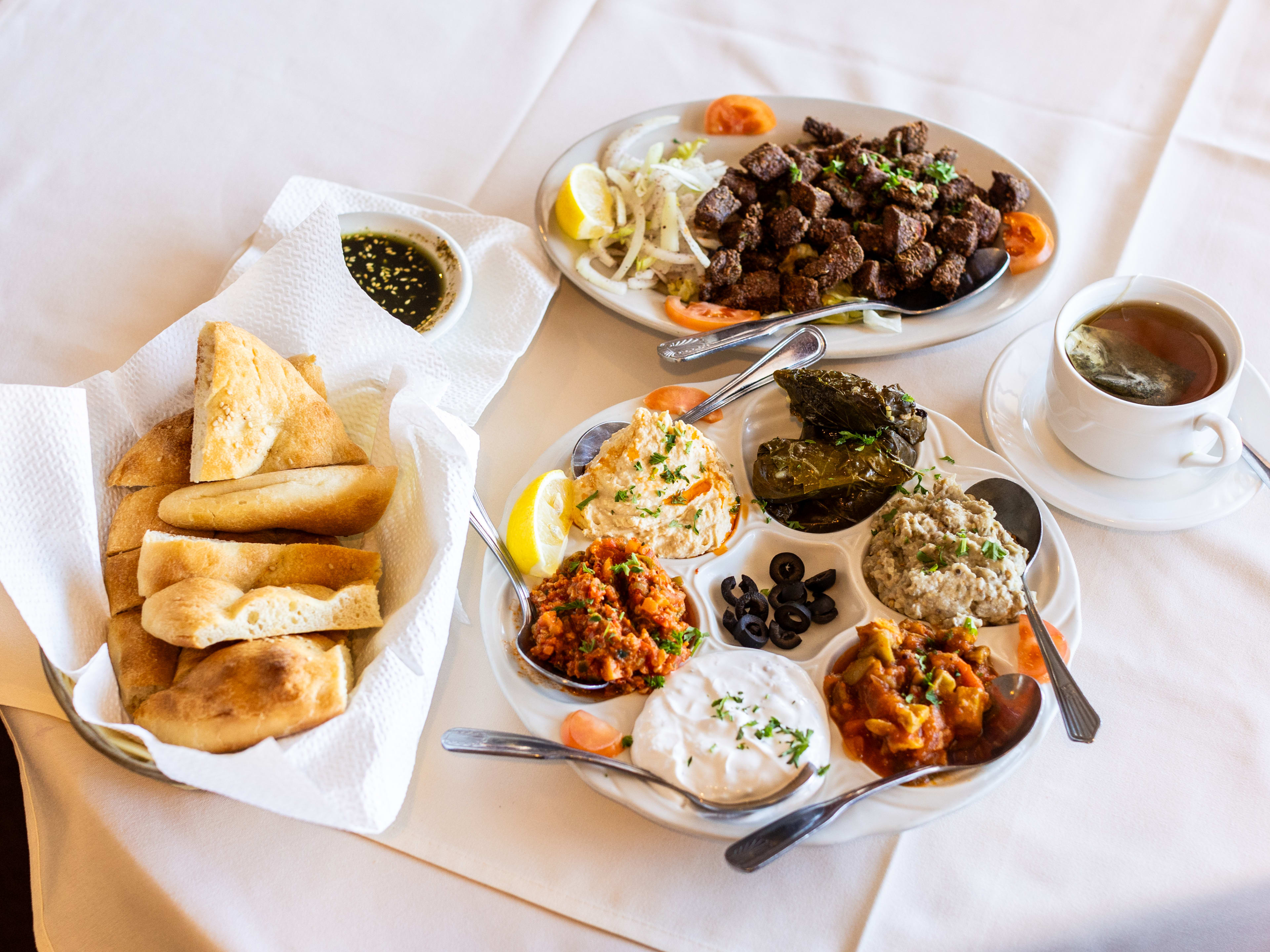 A variety of dishes from Empire Turkish Grill served on a table with a white table cloth.