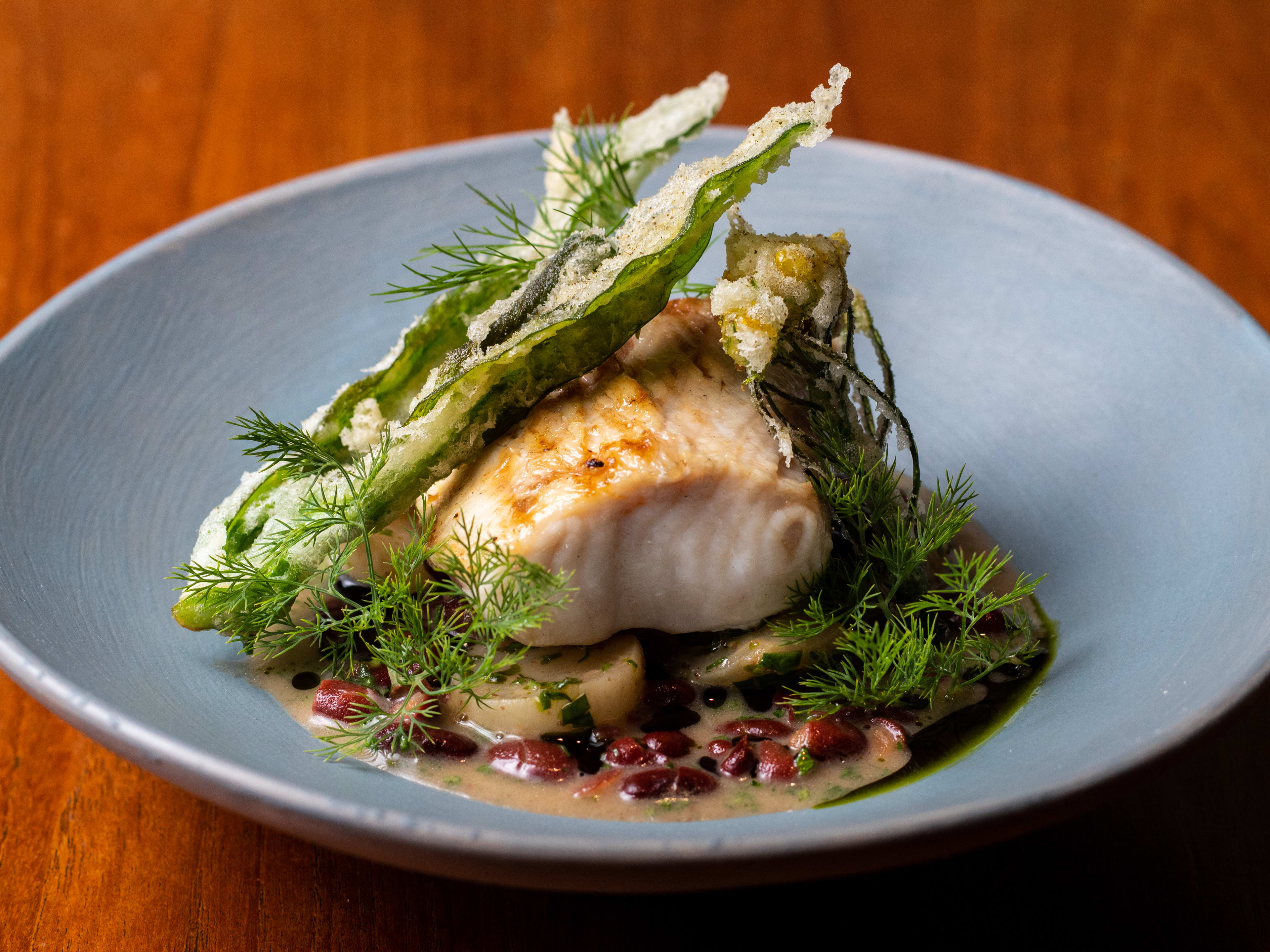 A grilled swordfish surrounded by herbs.