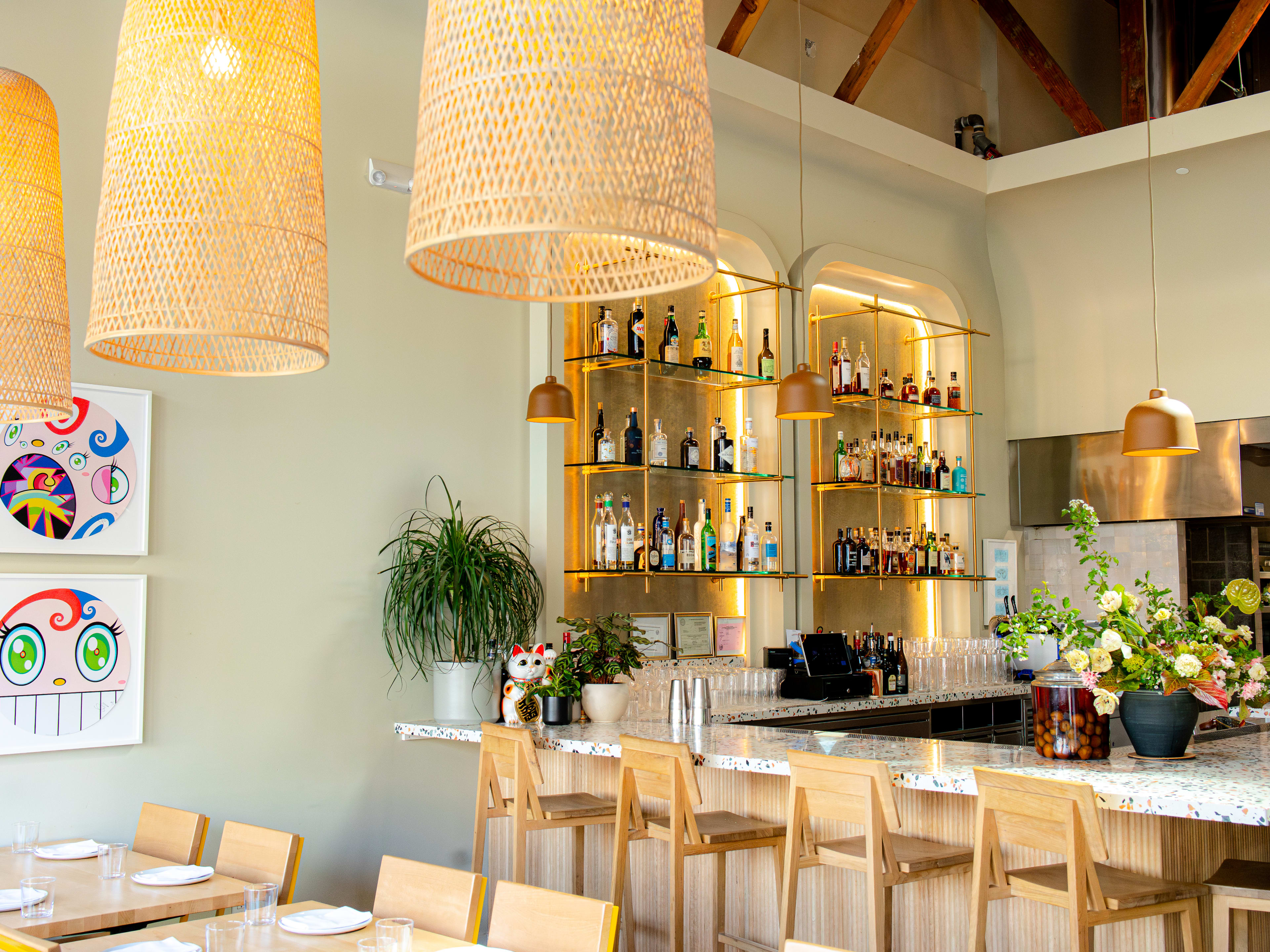 dining room with light colored wood furniture, straw lighting fixtures, and colorful art