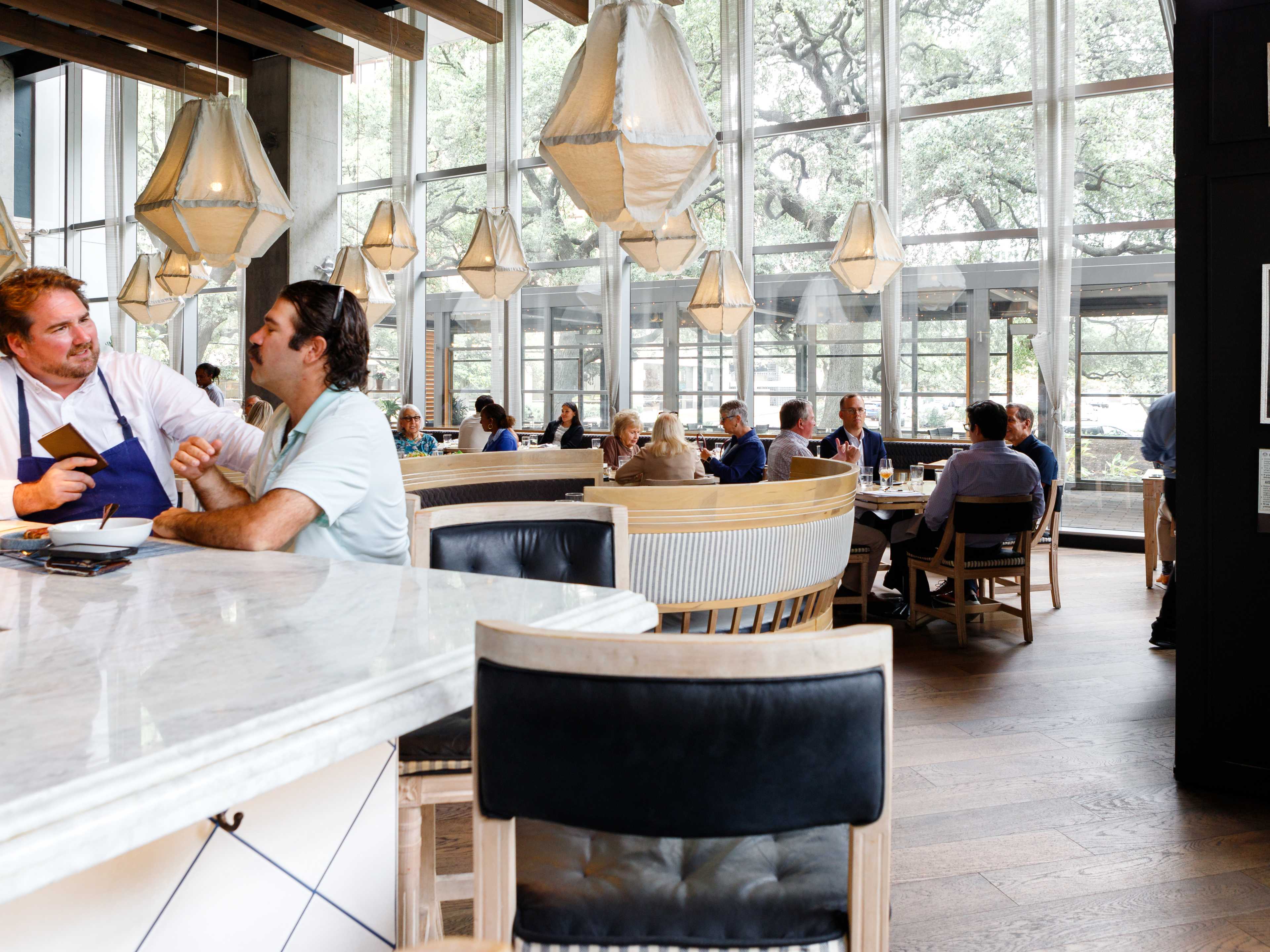 Two people at the bar and other people dining at tables at the natural light filled Eunice.