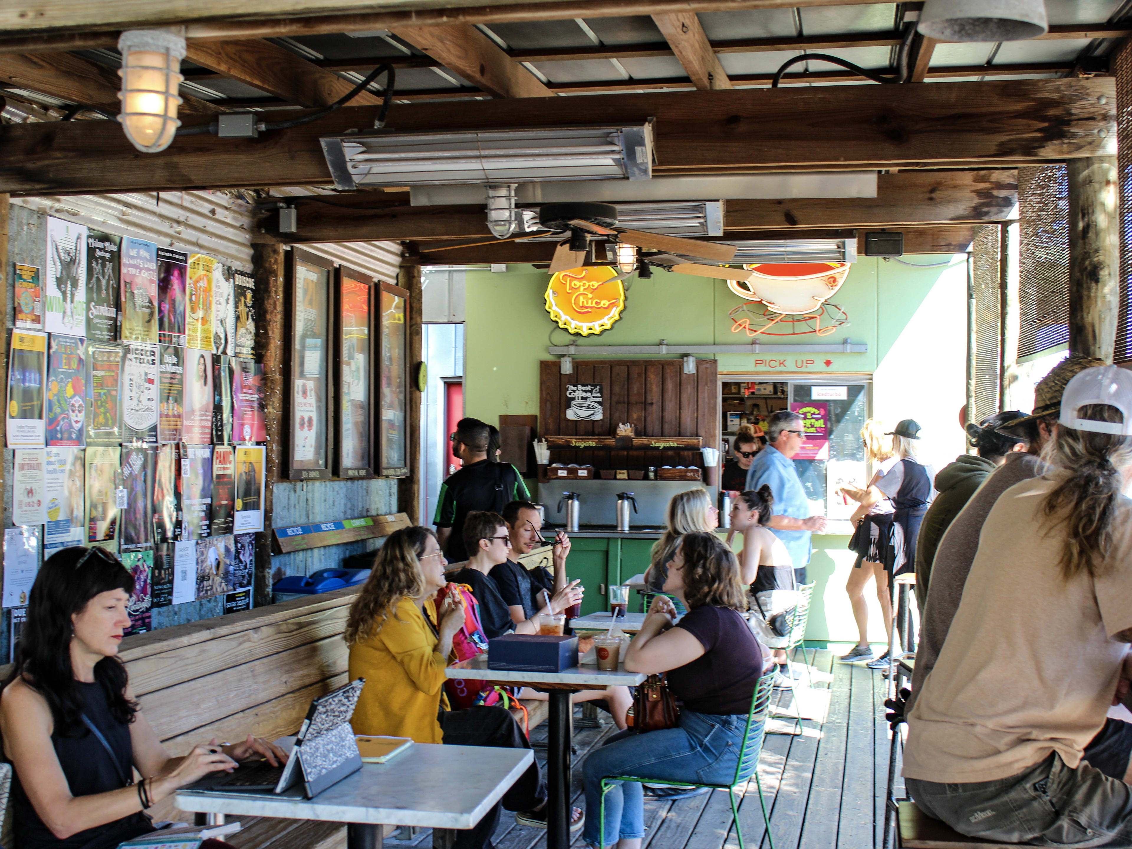 People sit and chat or work at tables and a counter bar inside Jo's coffee.