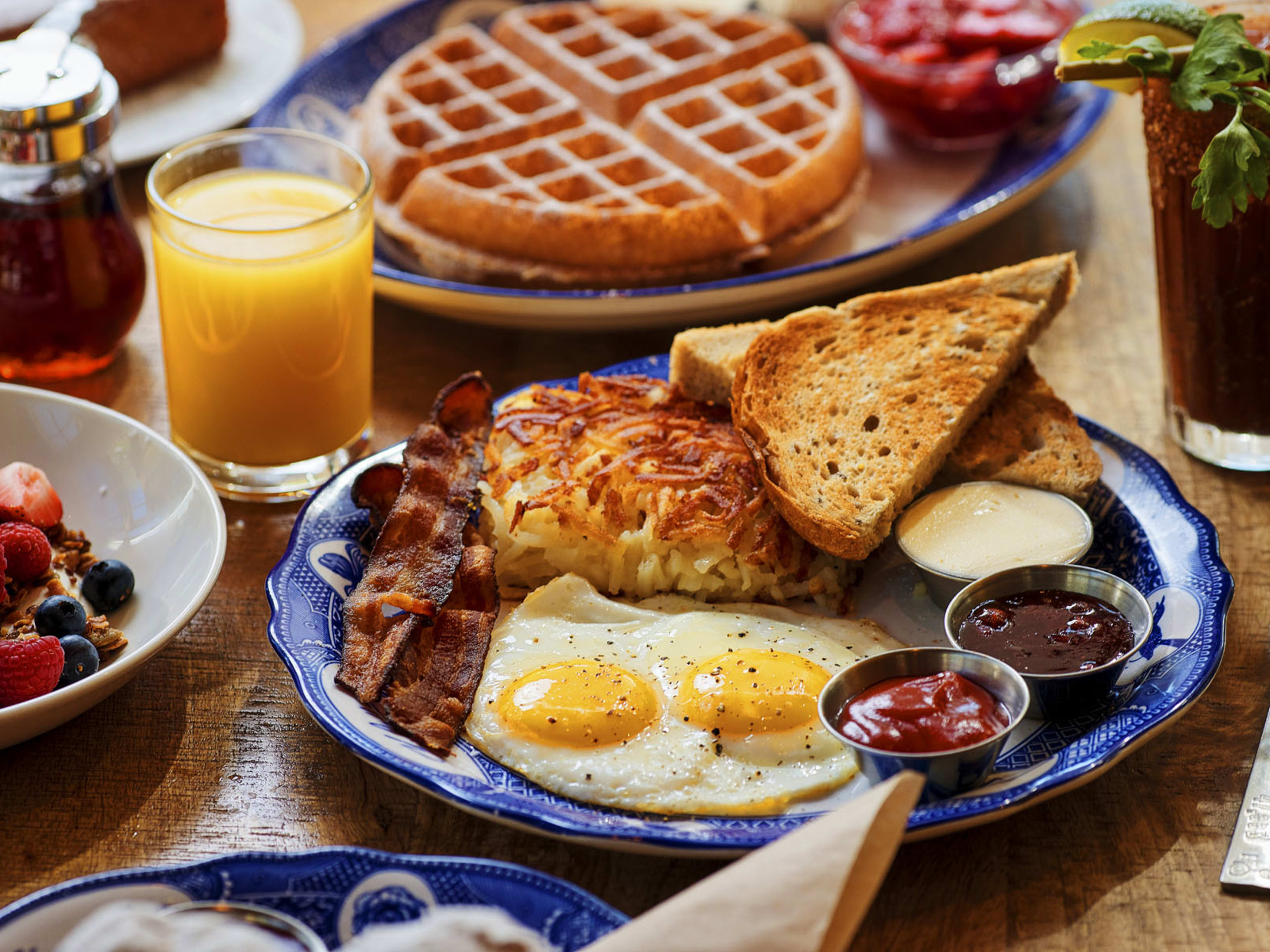 breakfast spread of OJ, coffee, eggs, toast, bacon, hash browns