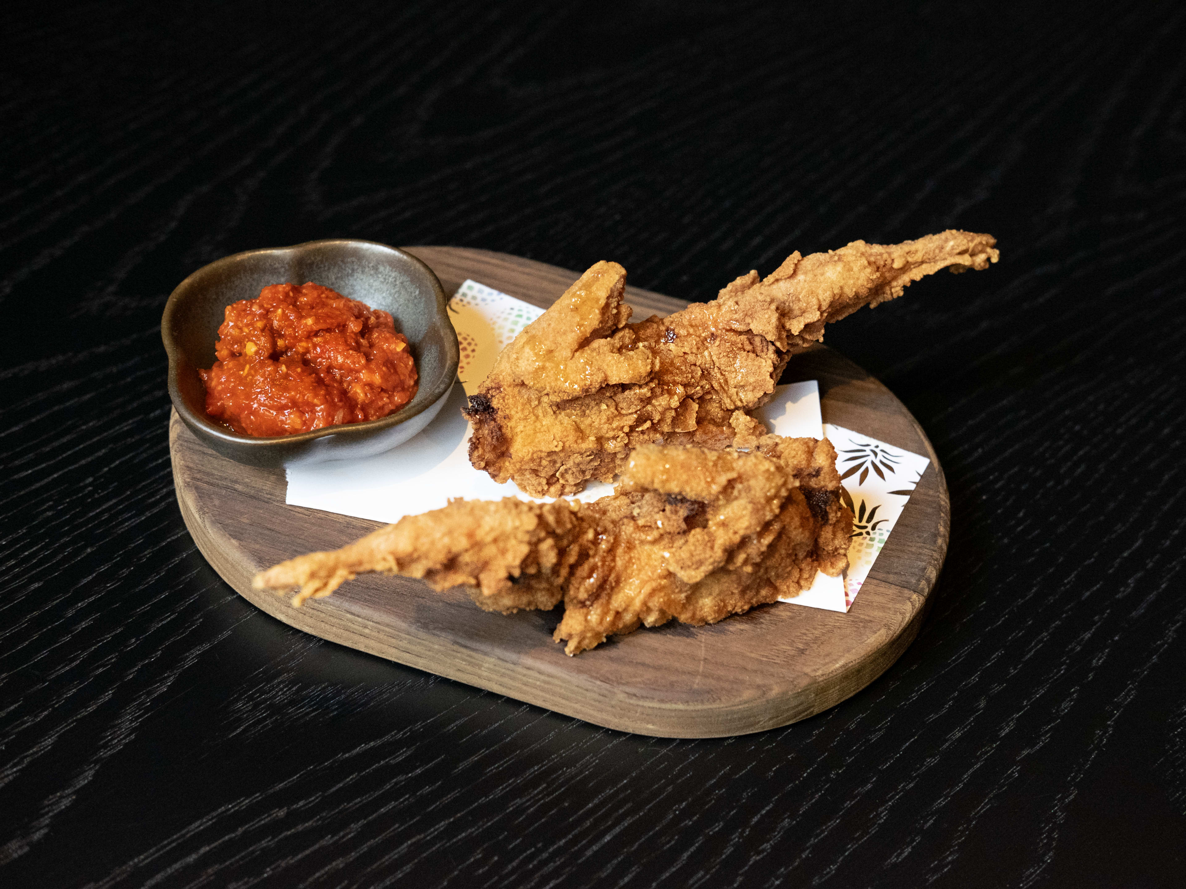 two pieces of fried quail served next to spicy sauce