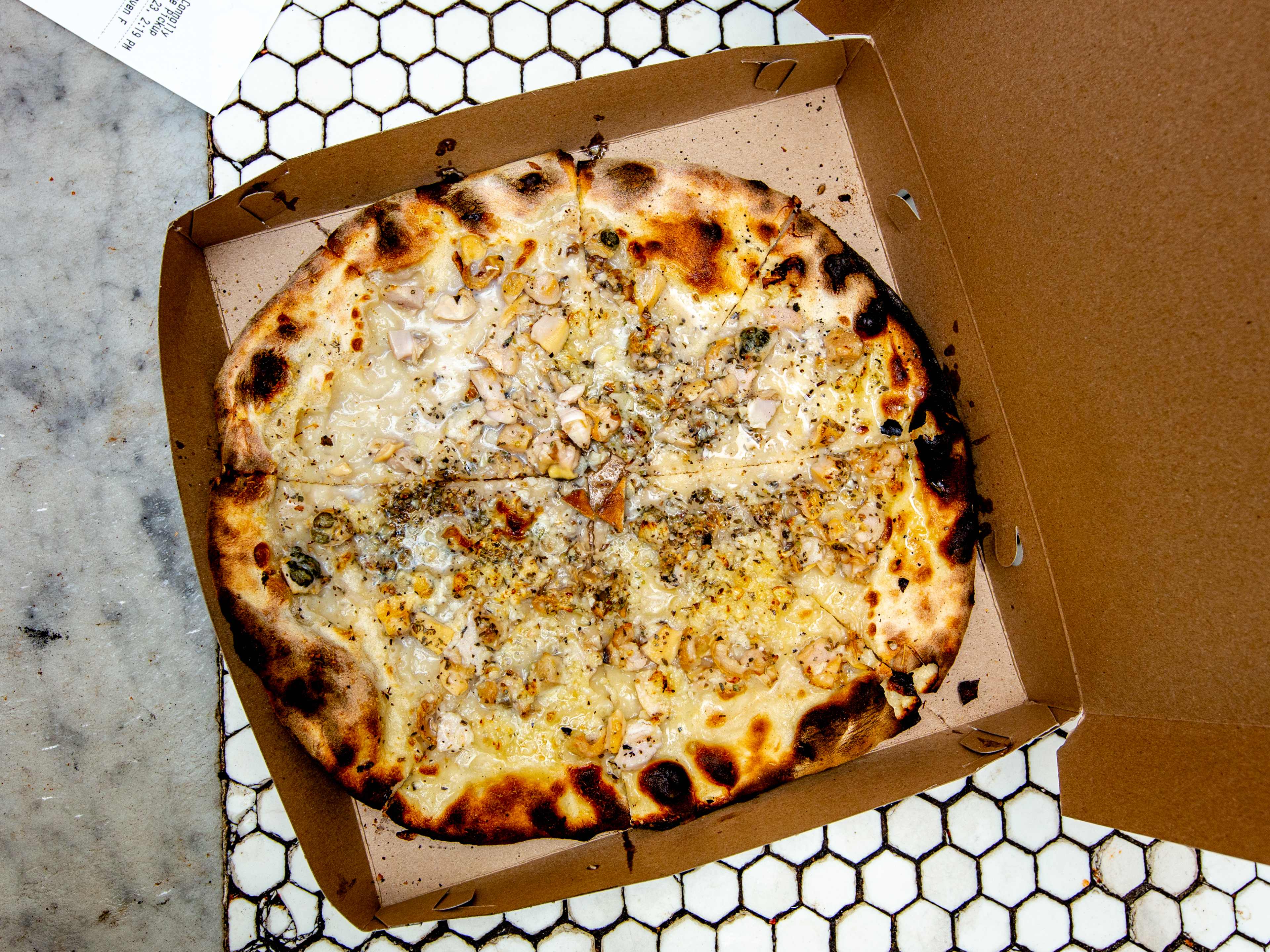 The clam pie at Frank Pepe's pizza in New Haven, in a box on tile