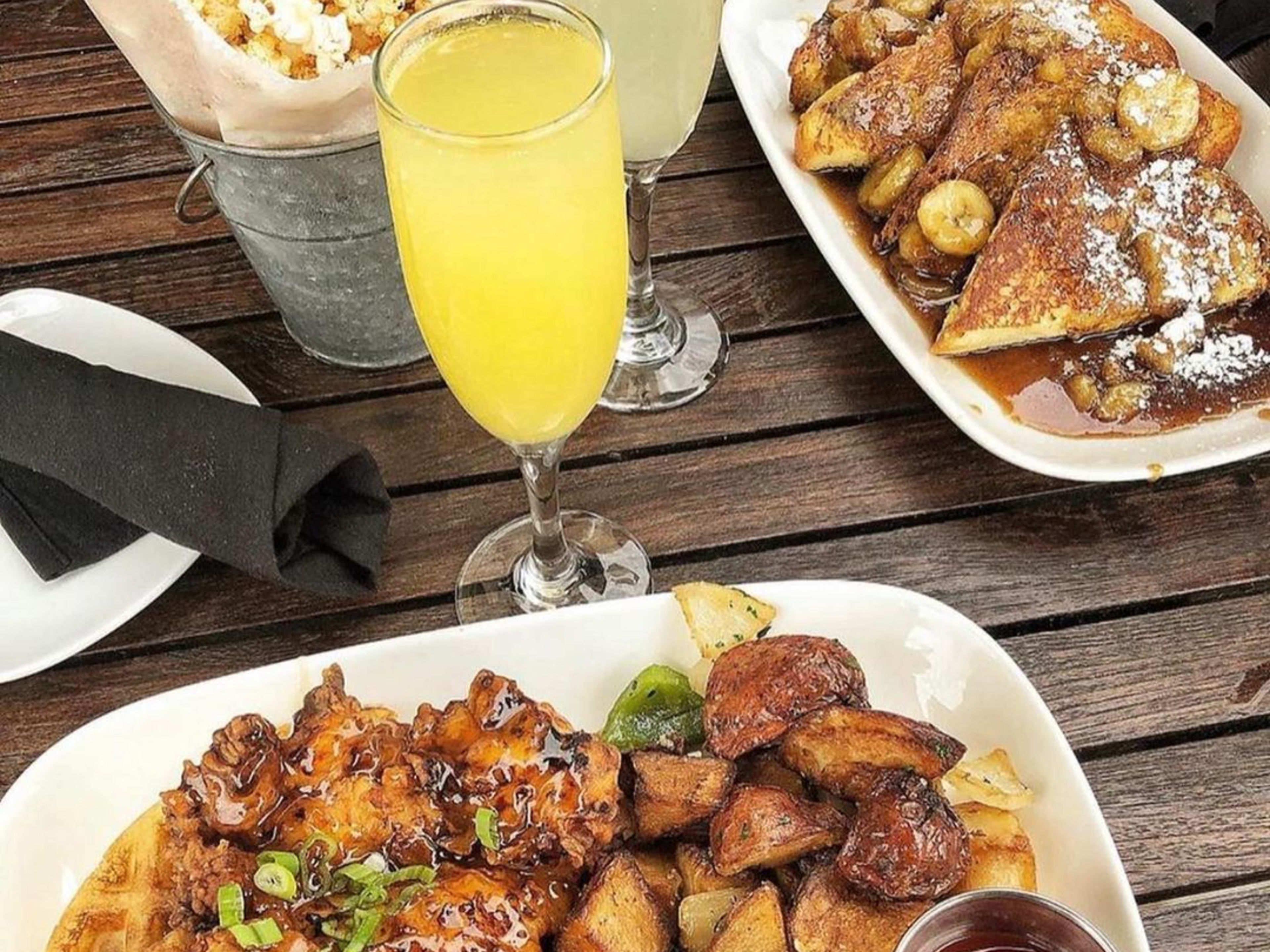 spread of chicken and waffles and french toast with glasses of mimosa and champagne