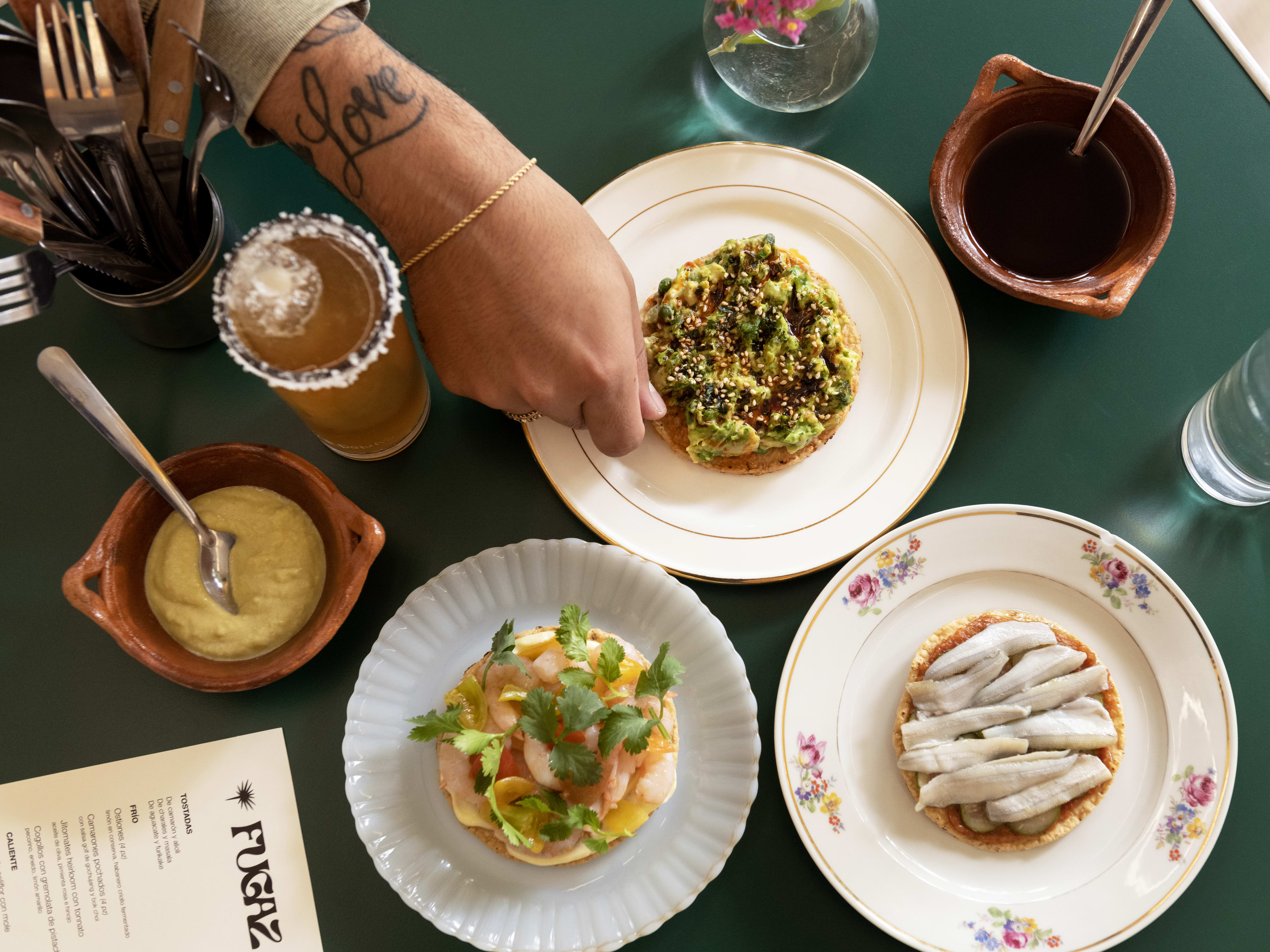 Spread of small dishes at cocktails on green table at Fugaz